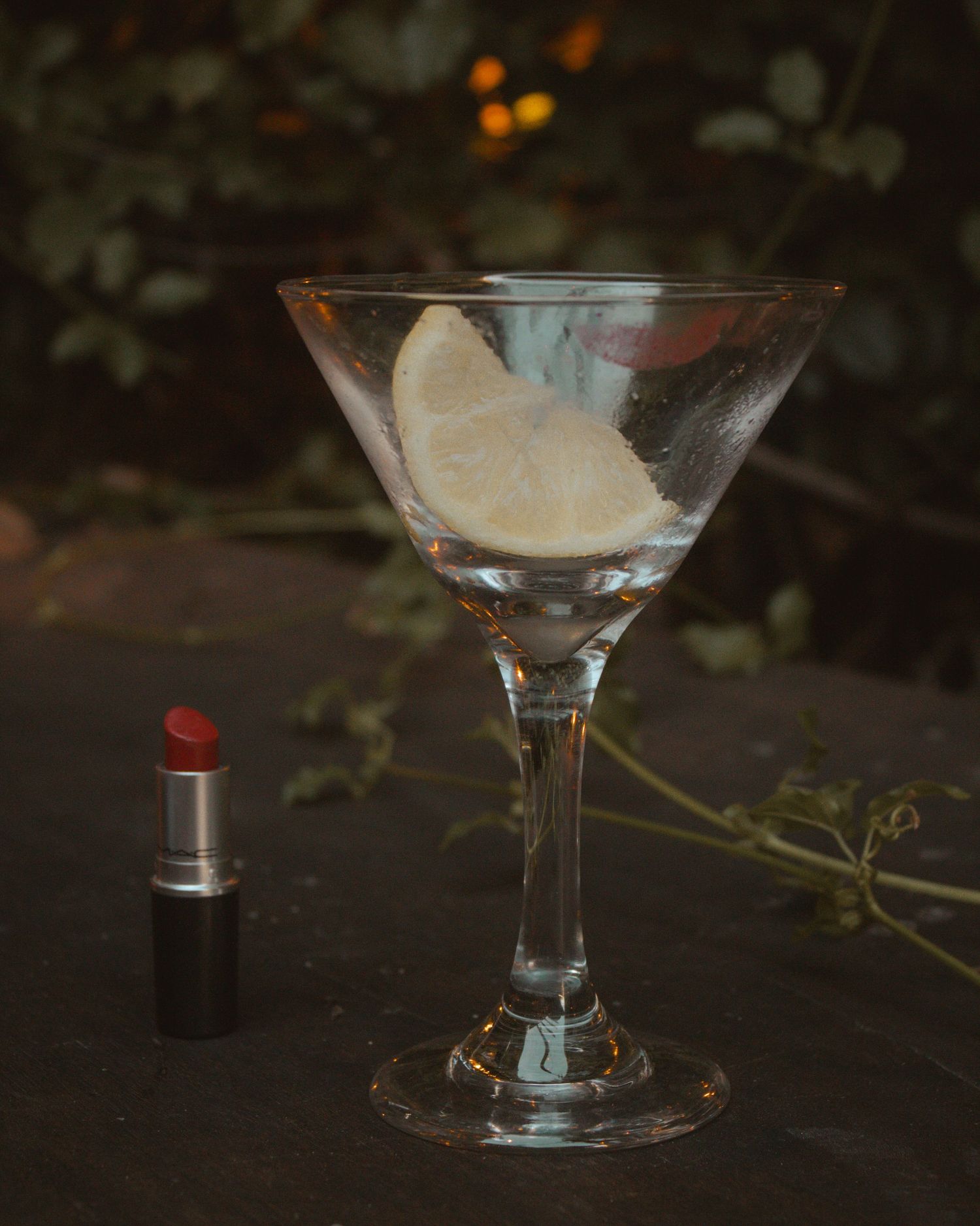 An empty martini glass with a lipstick stain sits elegantly against a dark background.