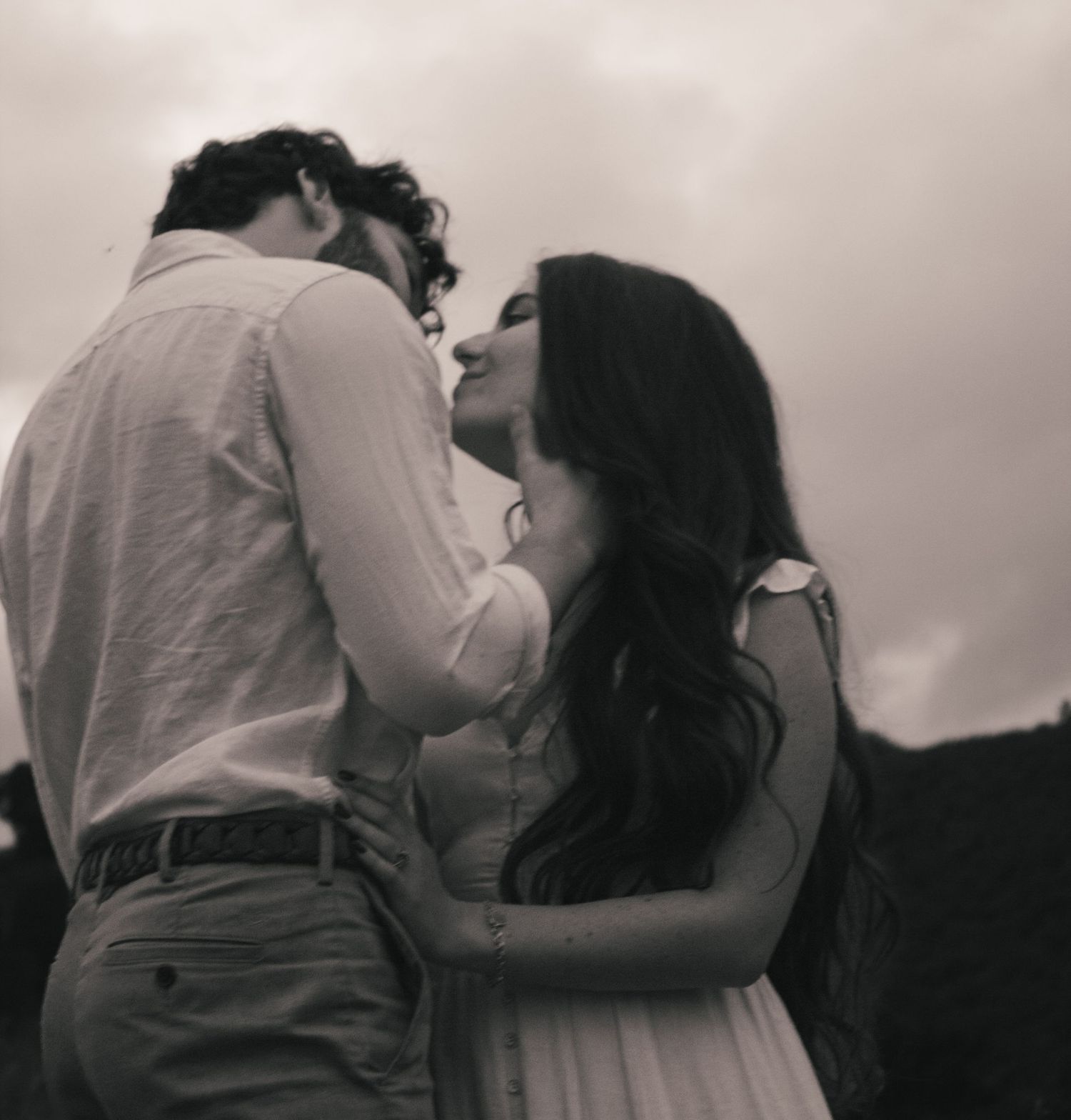 A romantic black and white photo series showing tender moments between a couple embracing and kissing.