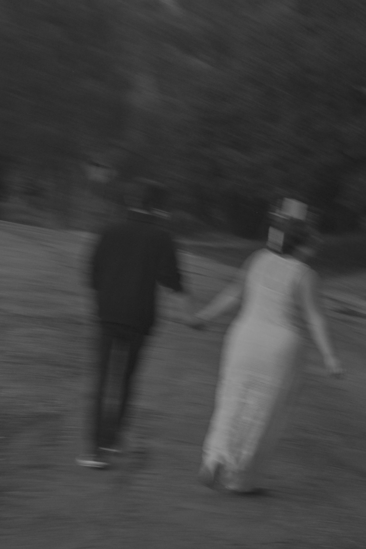 A blurred black and white photograph shows people walking in a park or garden setting.