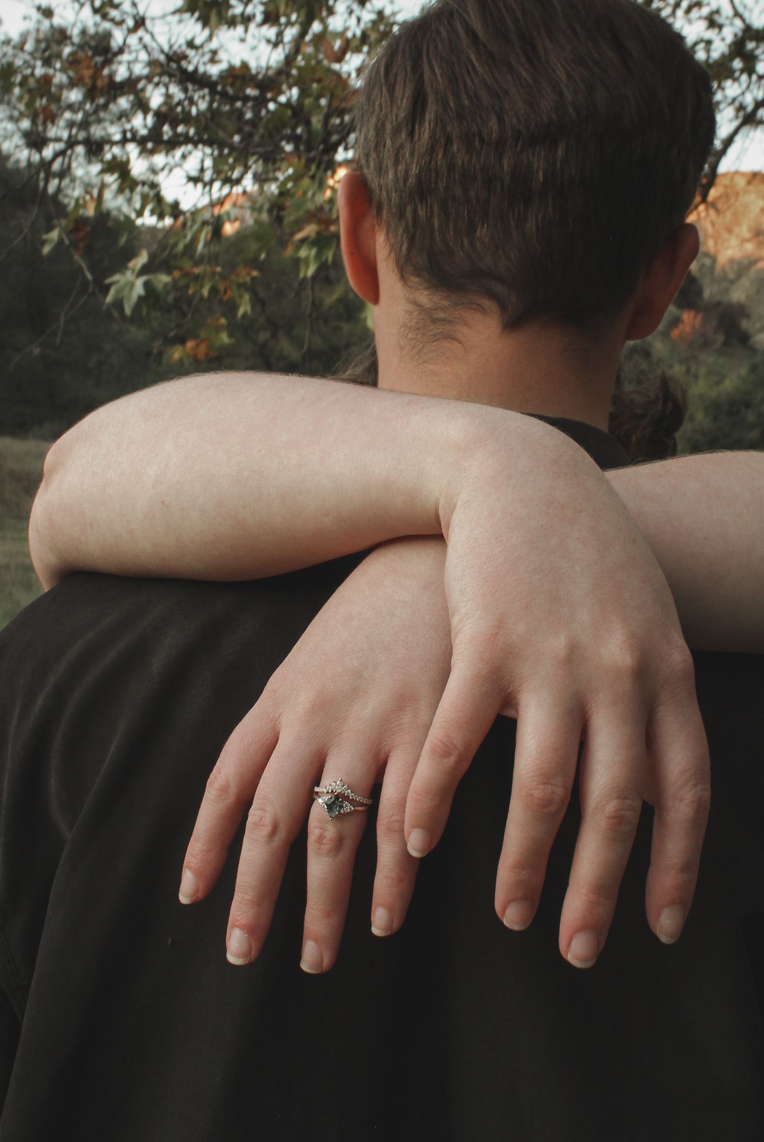 Close-up sequence of hands resting on a shoulder wearing a black shirt, with an engagement ring visible.