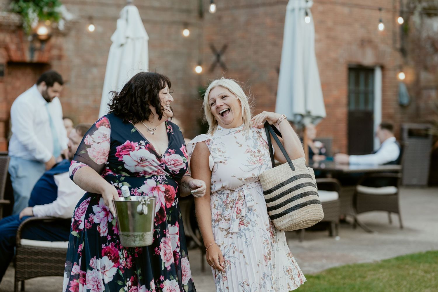 Wedding guests sharing joyful moments on outdoor patio with string lights.
