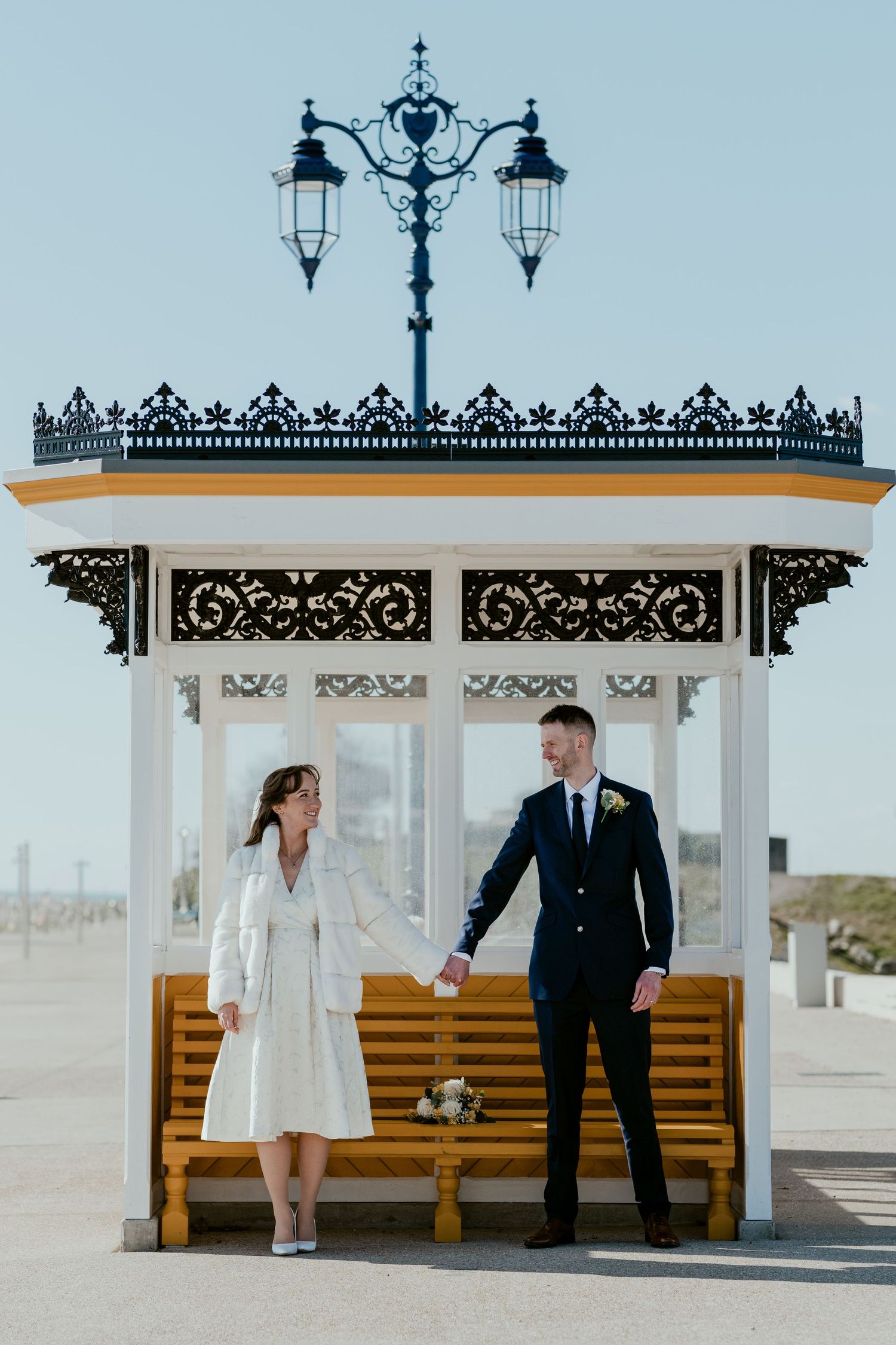 A Victorian-style seaside shelter with ornate ironwork and wooden benches.