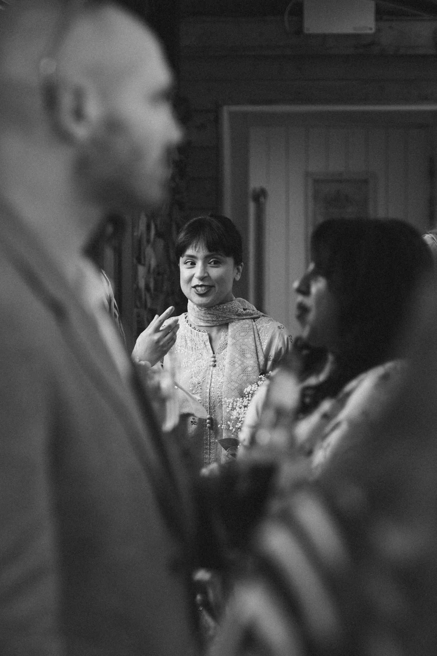 Black and white candid reception scene with guests laughing and celebrating.