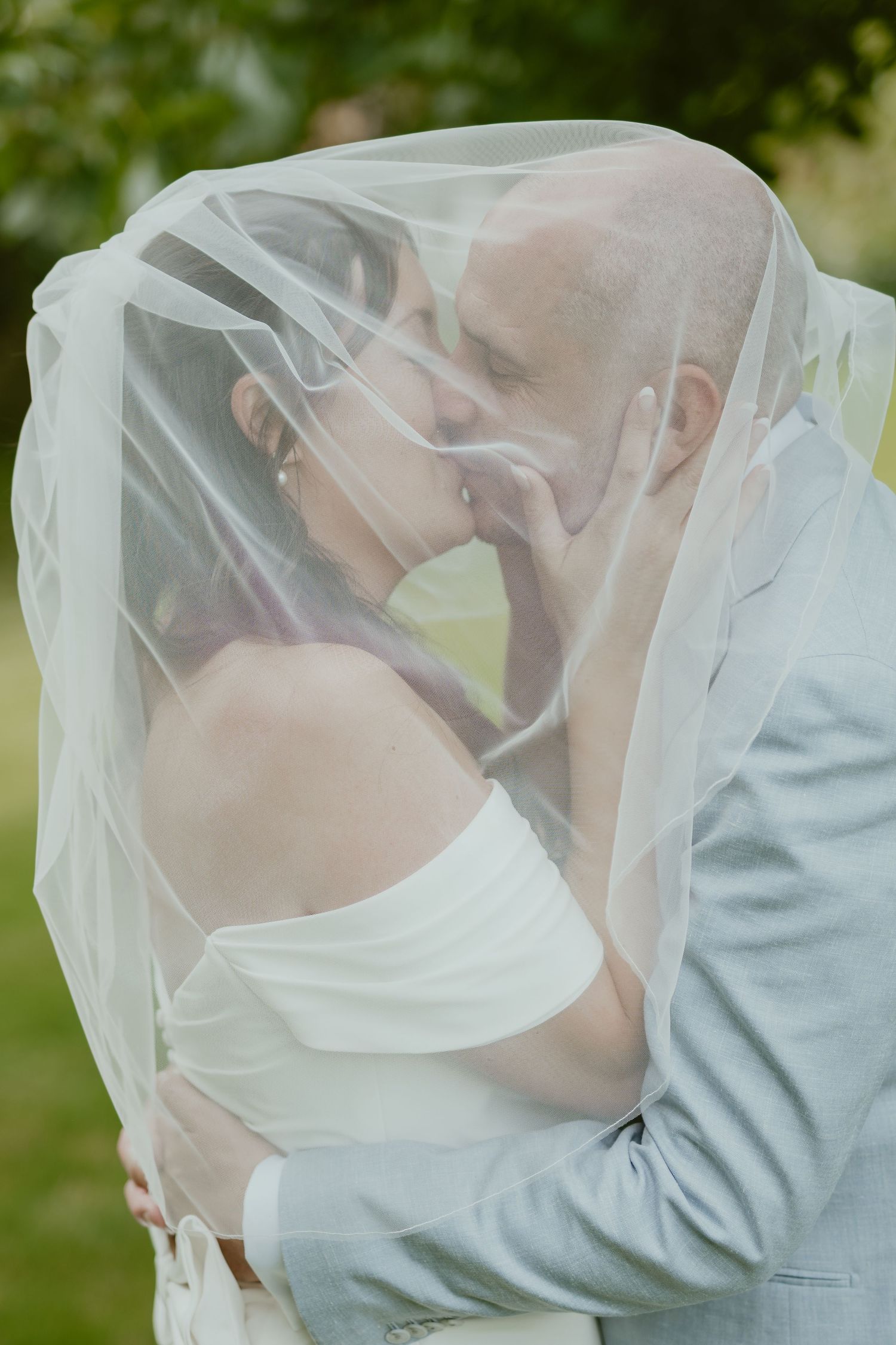 Romantic moment under a wedding veil in an outdoor garden setting.