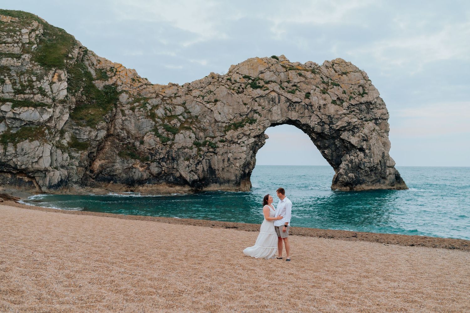 A couple enjoys a scenic coastal view with dramatic rock formations and turquoise waters.