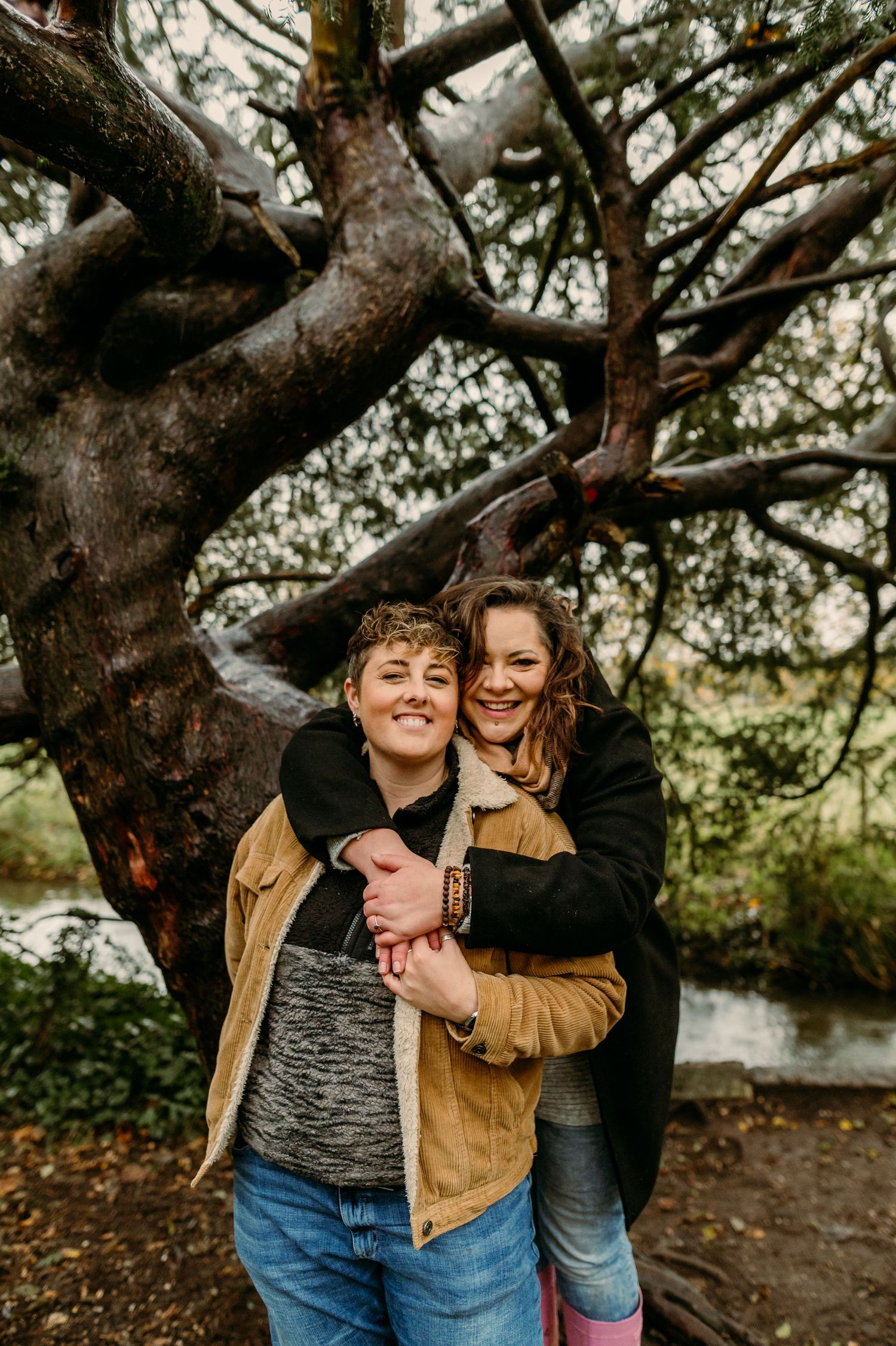 A playful autumn photoshoot under a large tree with warm lighting and natural surroundings.