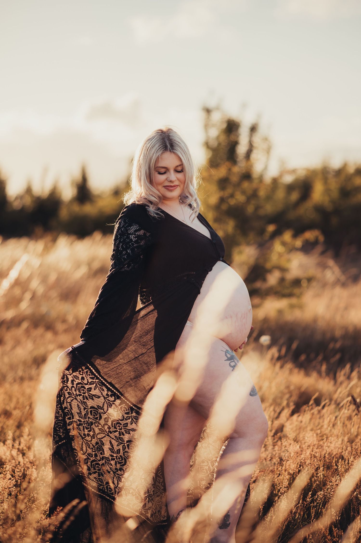 Artistic portrait through tall grass with warm sunset lighting and dreamy atmosphere.