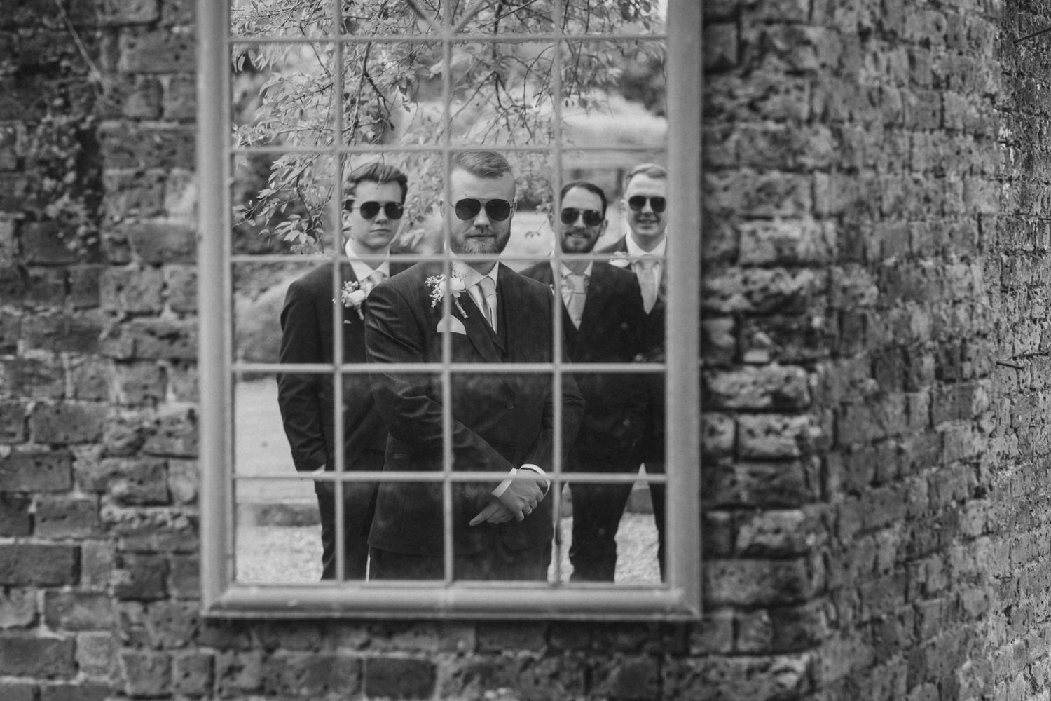 Wedding party poses playfully through historic stone building windows.