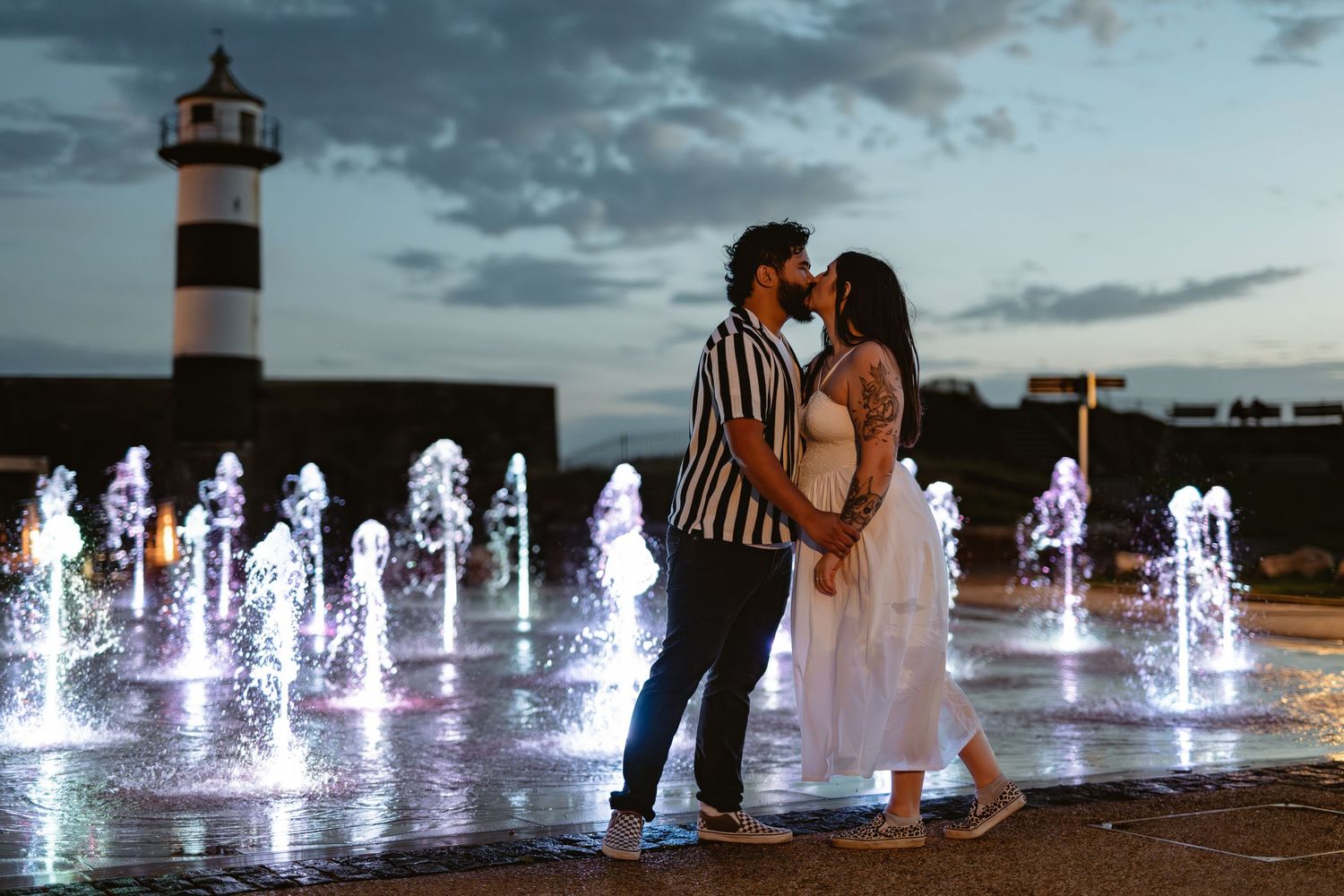 Silhouettes move through illuminated water fountains at night creating a magical atmosphere.