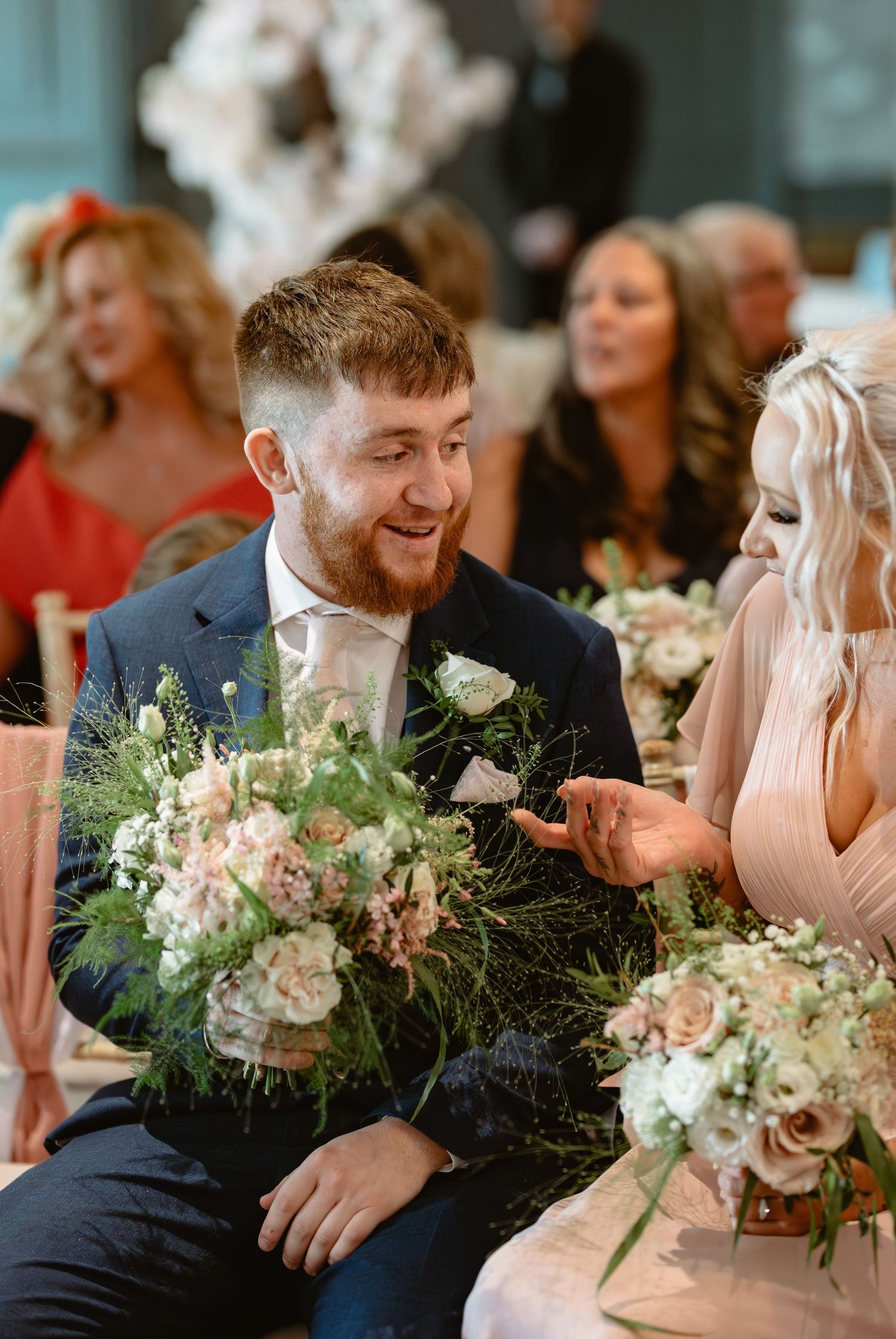 Wedding reception table decorated with elegant floral arrangements and guests enjoying conversation.