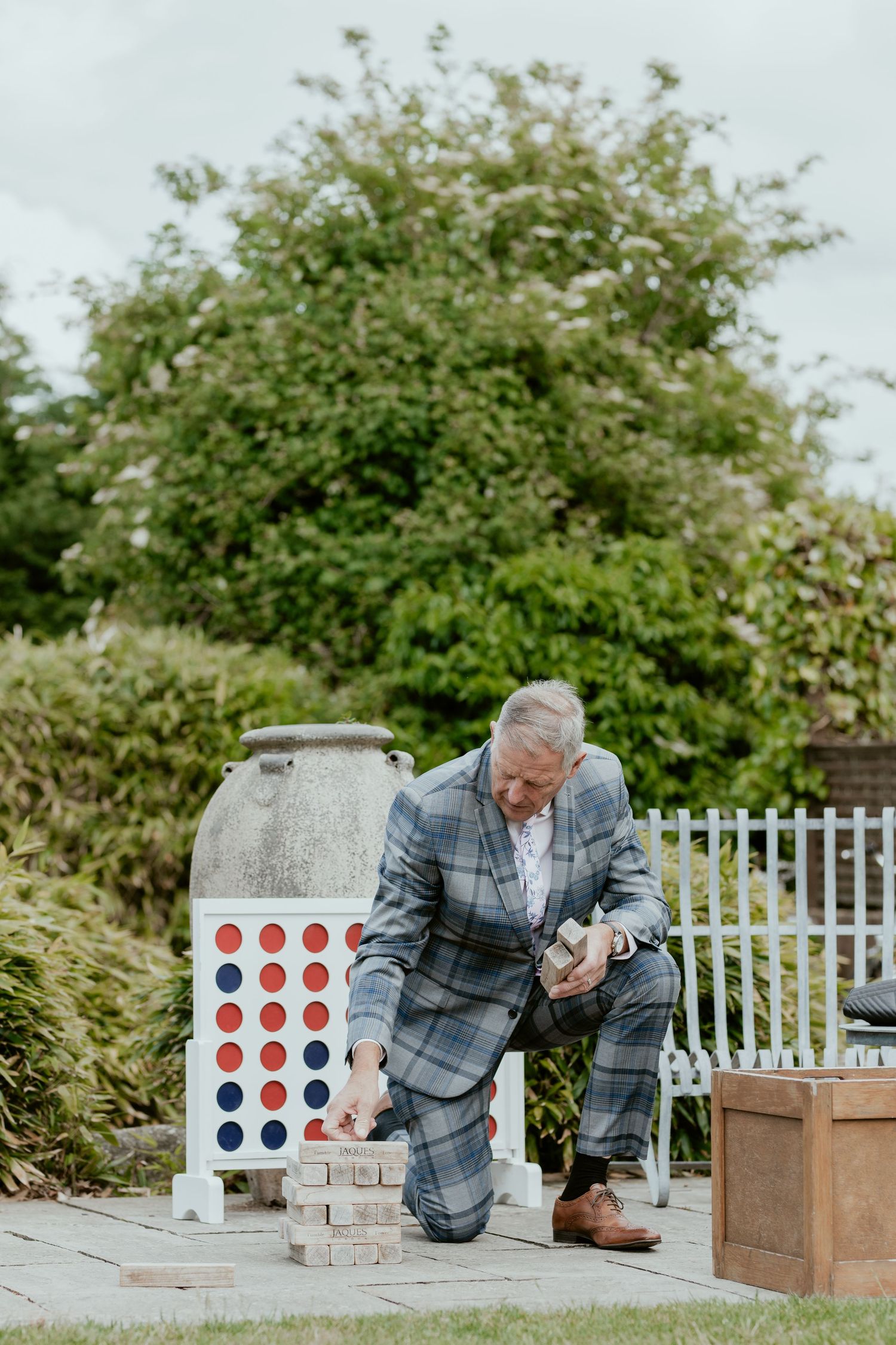 Person in plaid suit playing outdoor lawn games during wedding reception.