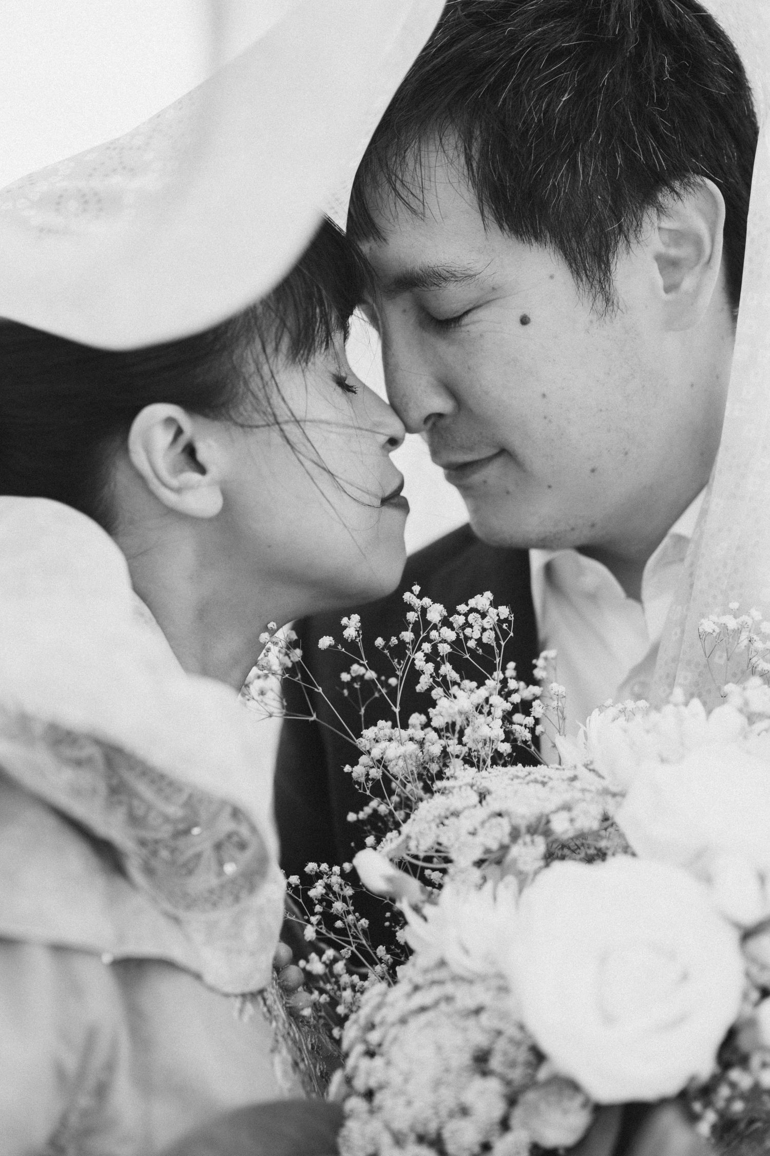 Black and white romantic portraits of a couple with delicate white flowers.