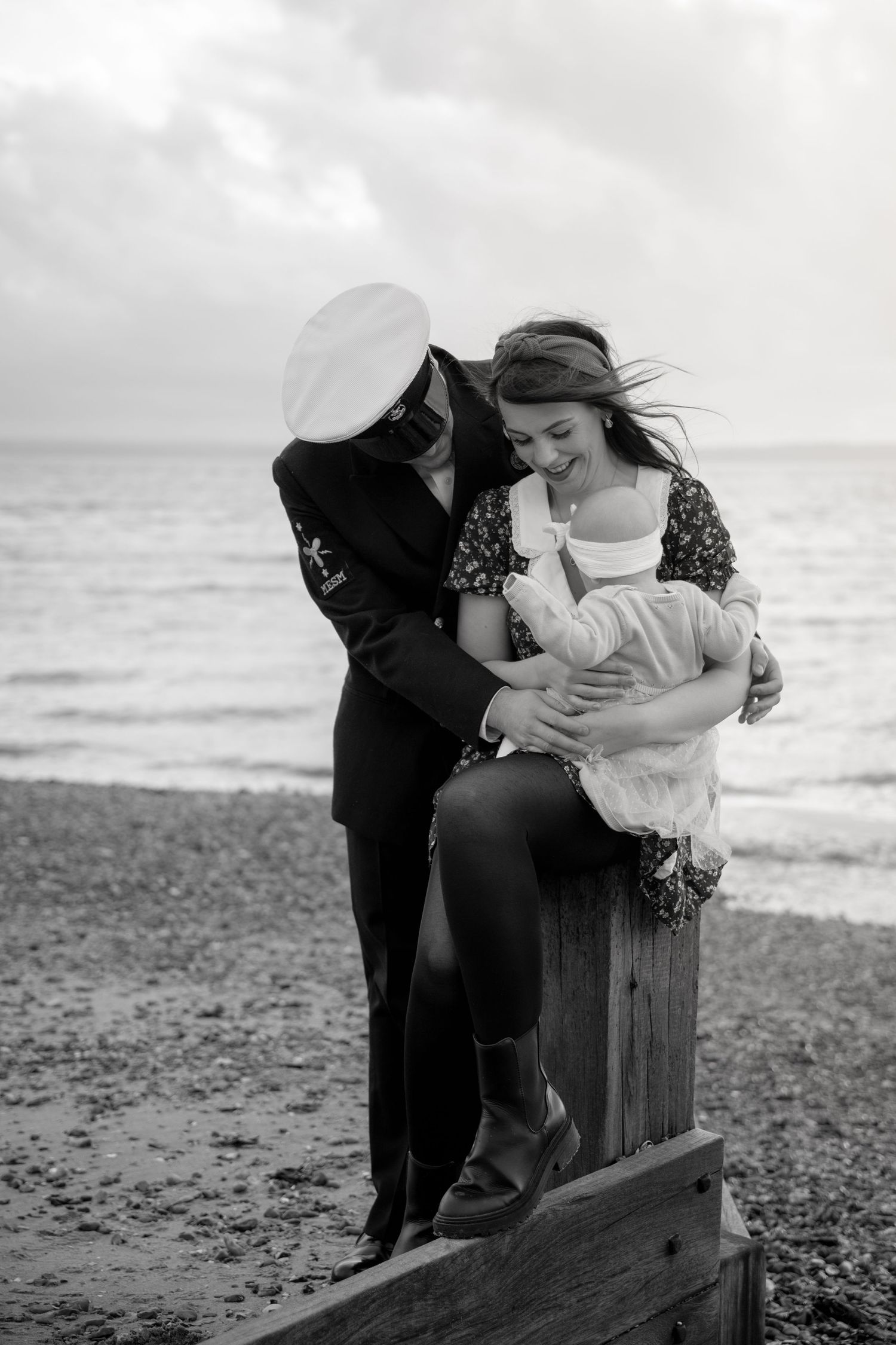A touching seaside moment captured in black and white on a rocky beach.