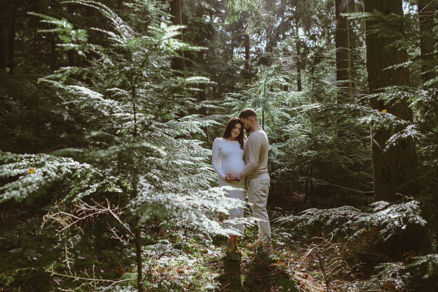 Romantic forest photoshoot among tall evergreen trees.
