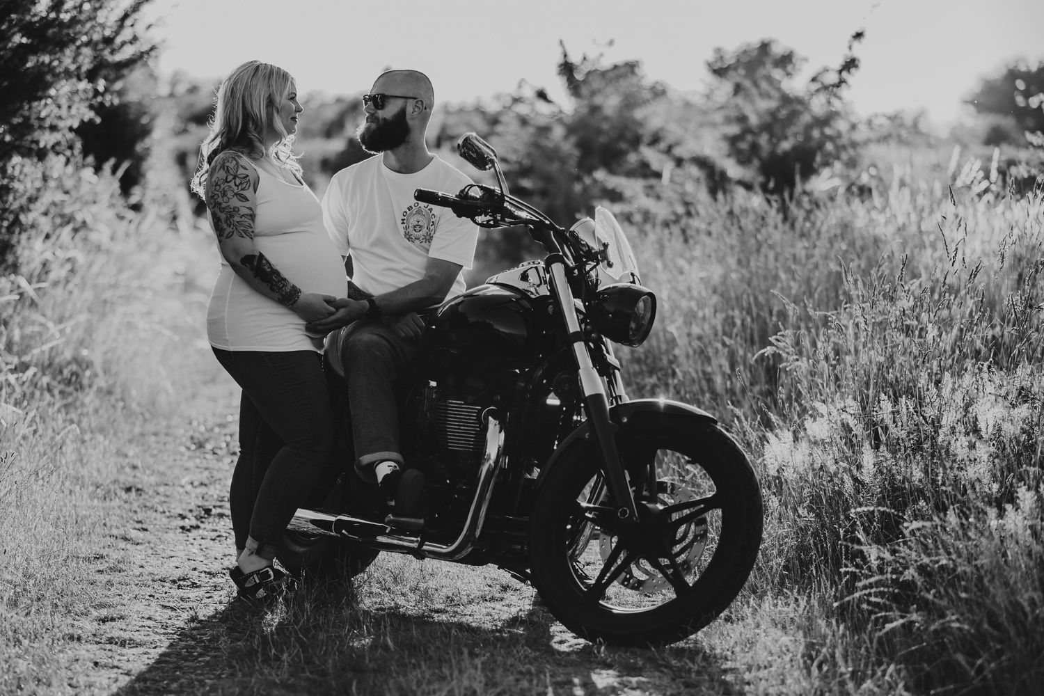 Vintage motorcycle parked in a rustic outdoor setting with dramatic black and white tones.