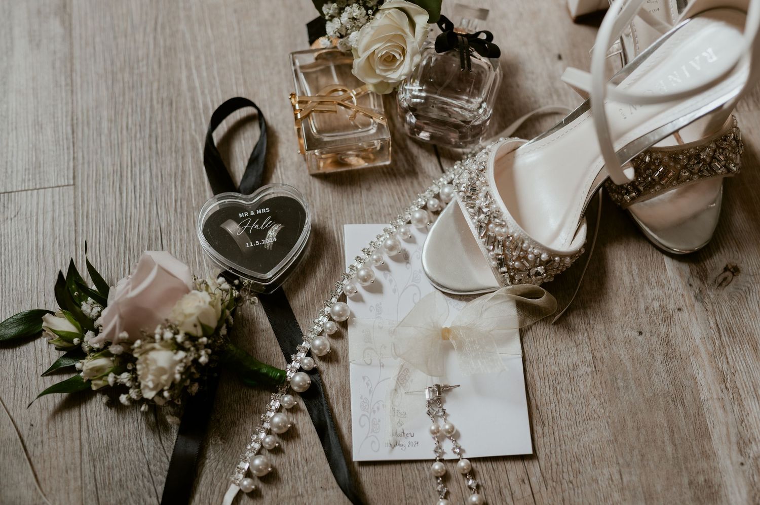 Wedding accessories and jewelry arranged on a wooden surface with a vintage aesthetic.