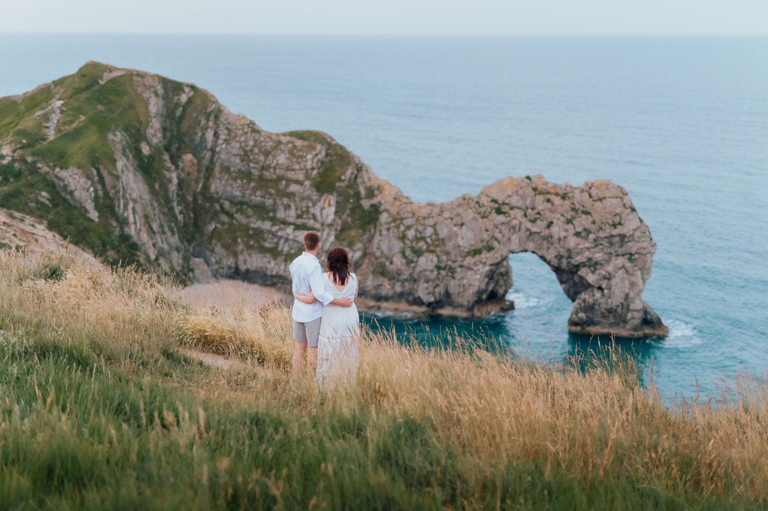 Scenic coastal cliffs and rocky formations along an ocean shoreline on a sunny day.