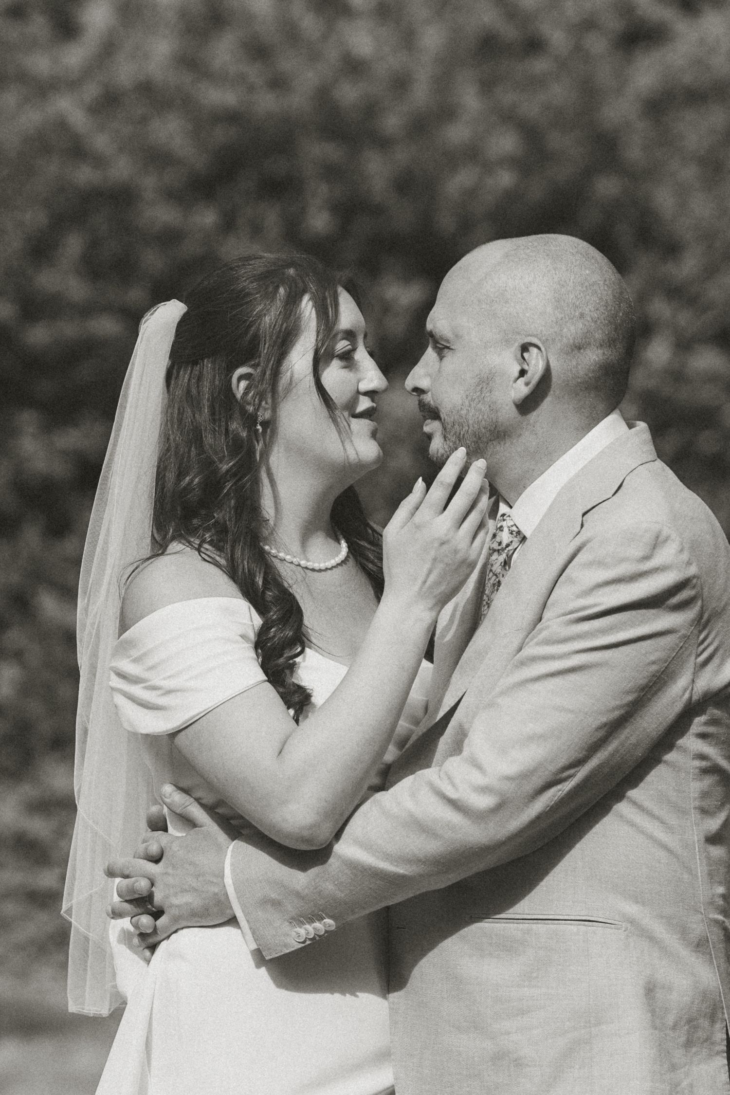 Romantic black and white wedding portrait captured in an intimate garden setting.