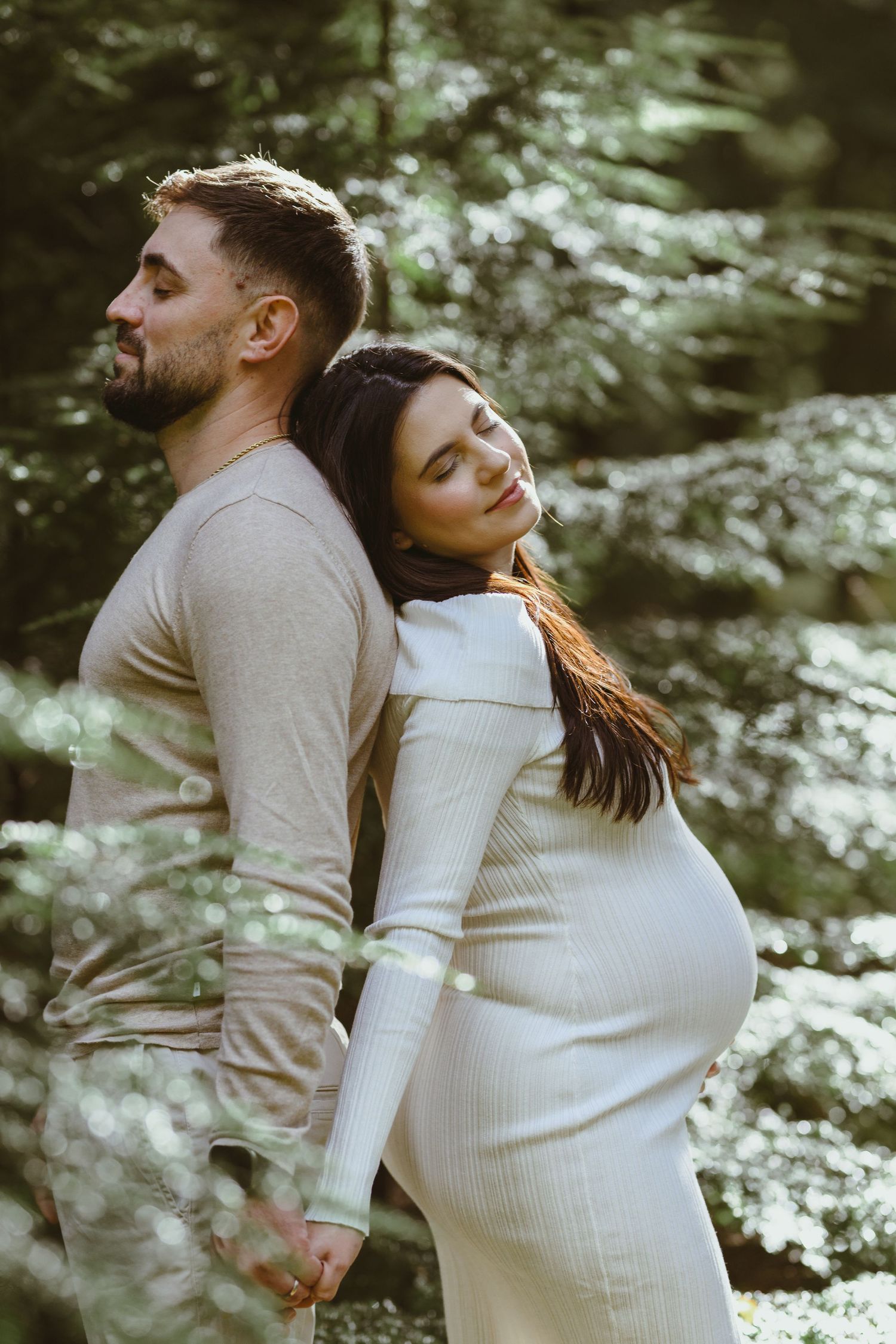 An intimate maternity photo series showing tender moments between a couple in a forest.