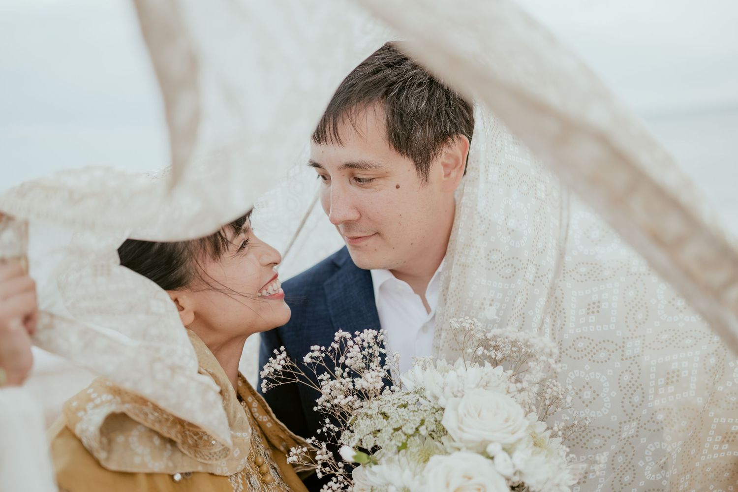 Romantic wedding couple sharing an intimate moment with white flowers.