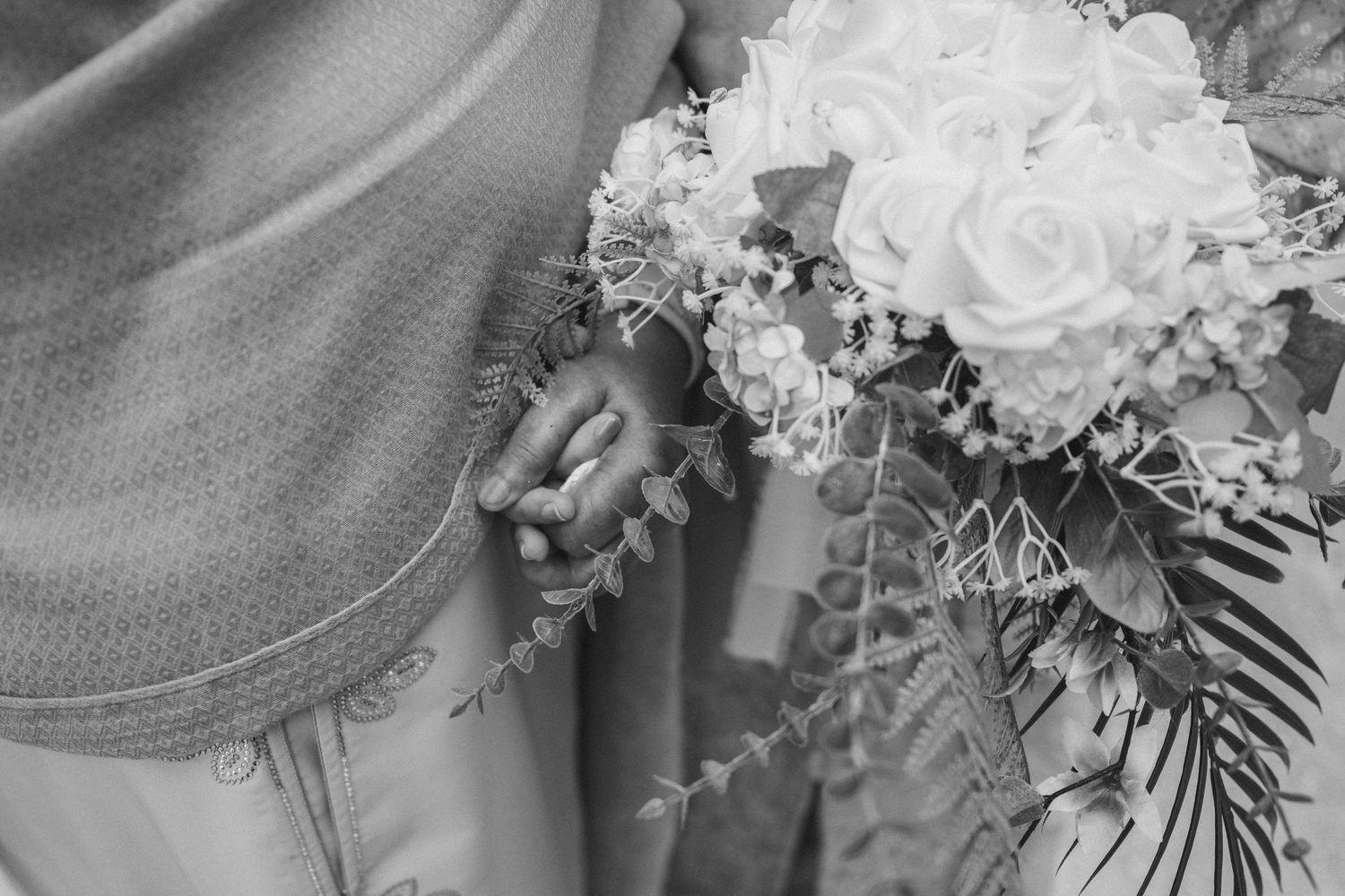 Close-up detail of a white floral bouquet with ferns against soft fabric.
