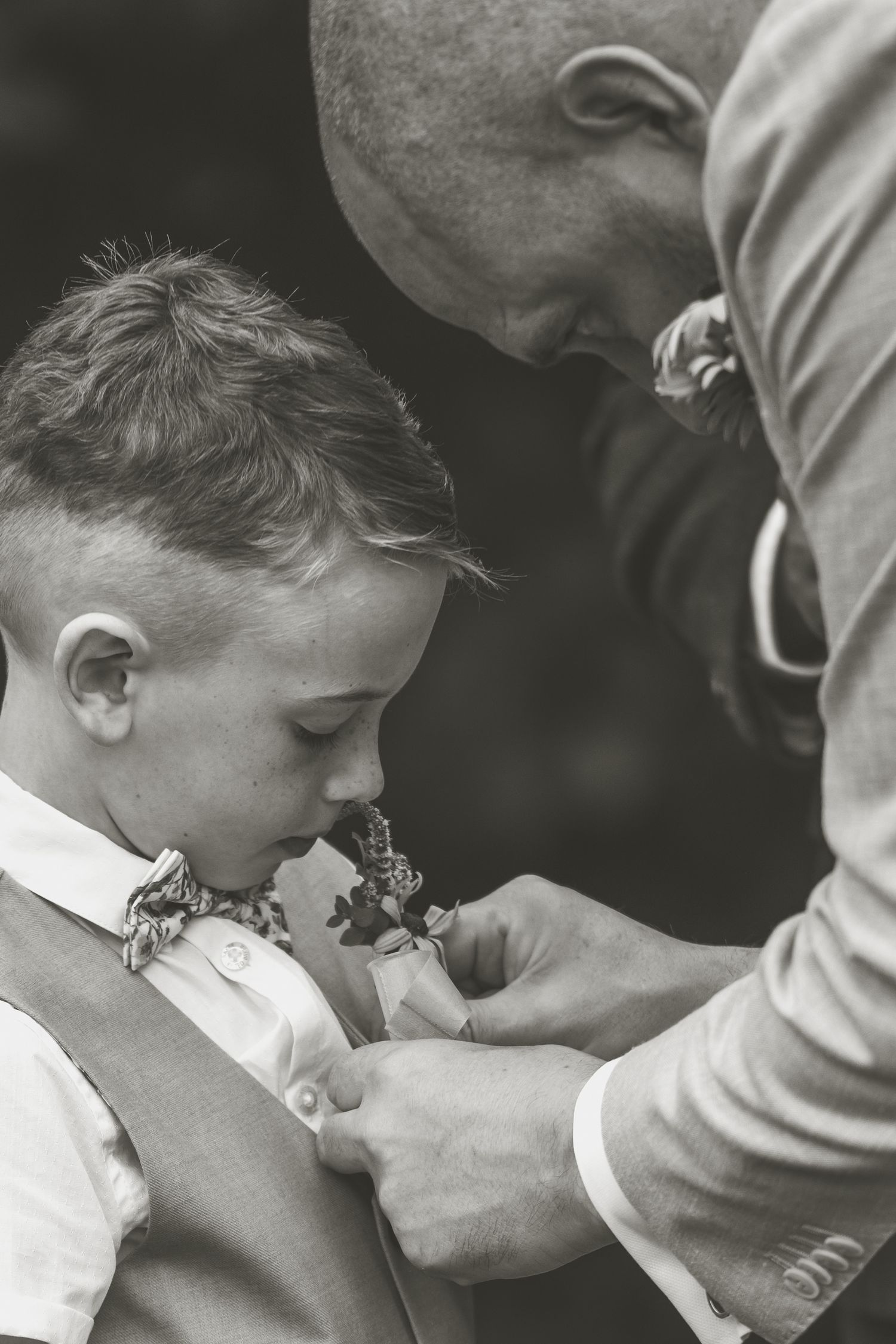 Black and white photo of someone adjusting a young boy's bow tie.