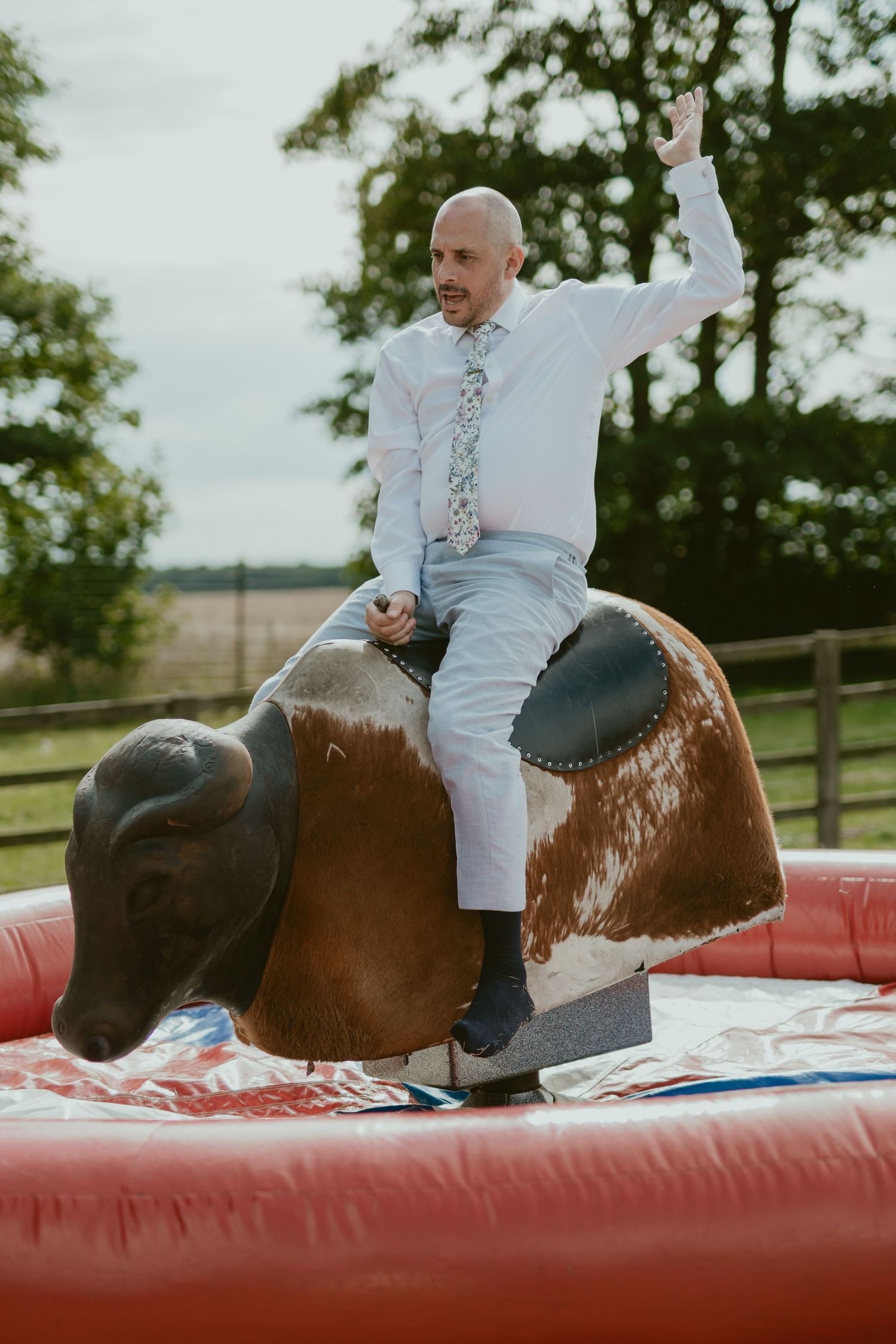 Person in white shirt riding a mechanical bull at an outdoor wedding reception.