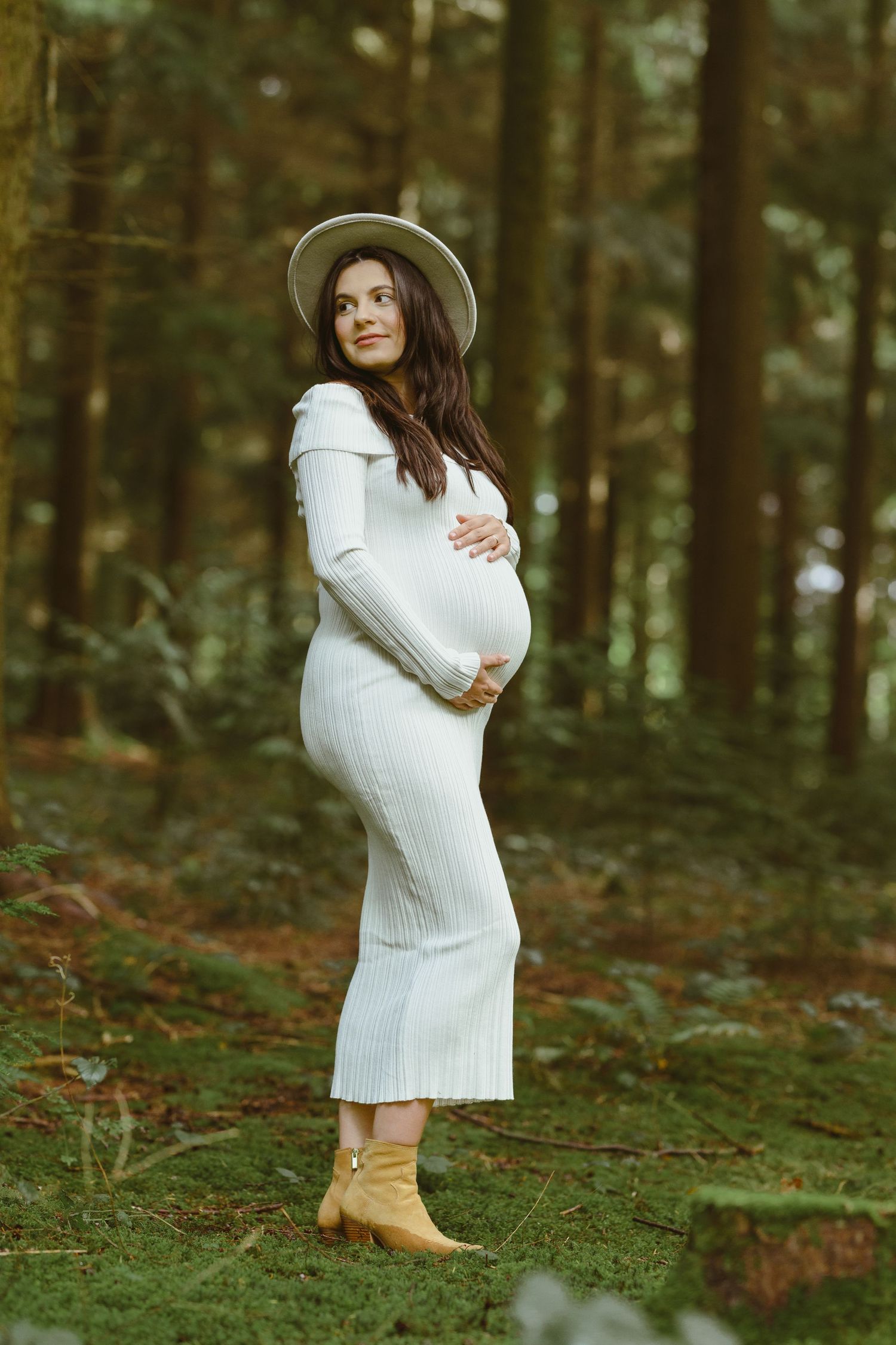 A maternity photo sequence showing joyful poses in a forest wearing a white sweater dress.