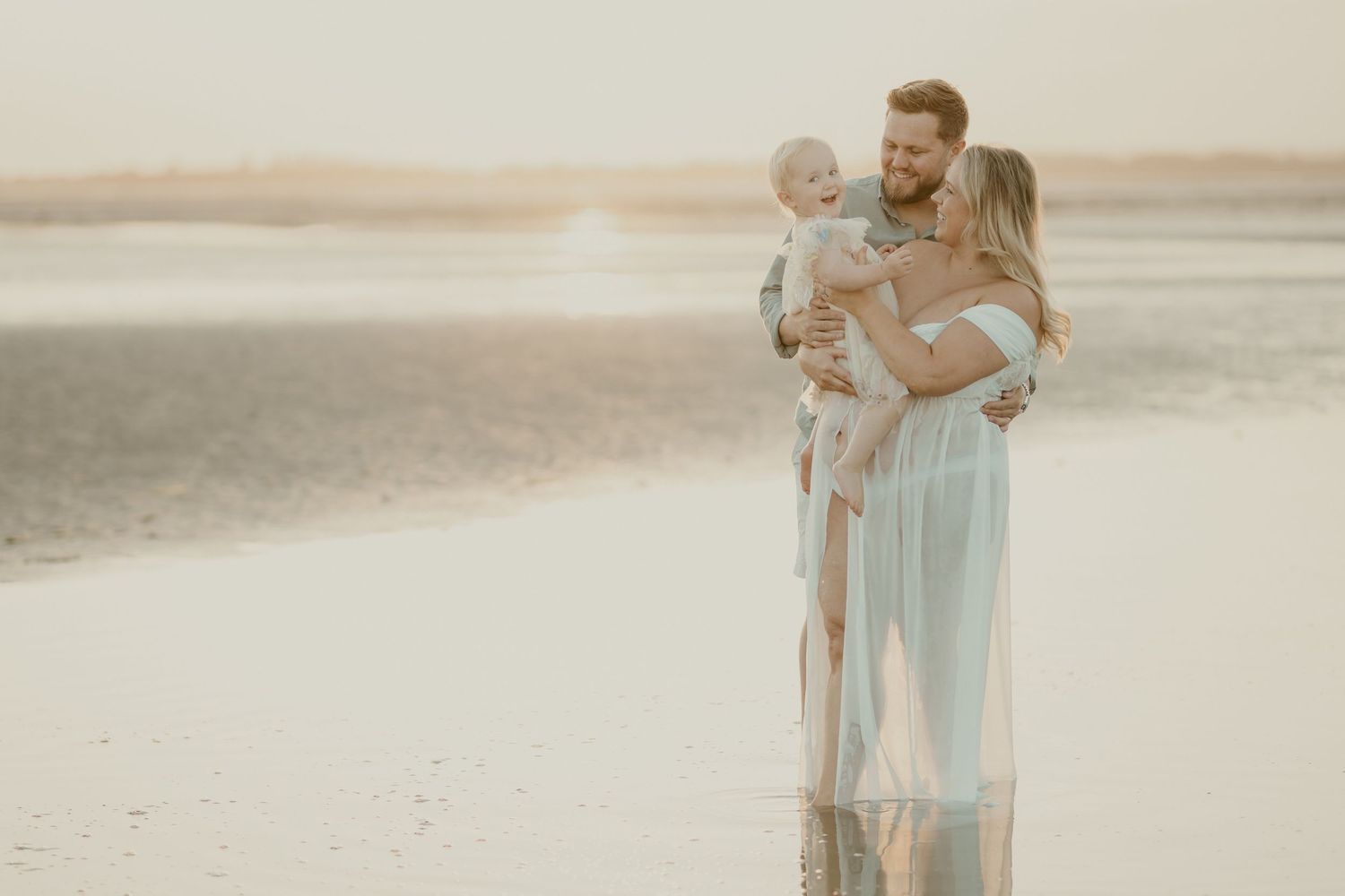 Tender beach maternity session with gentle waves and golden light.