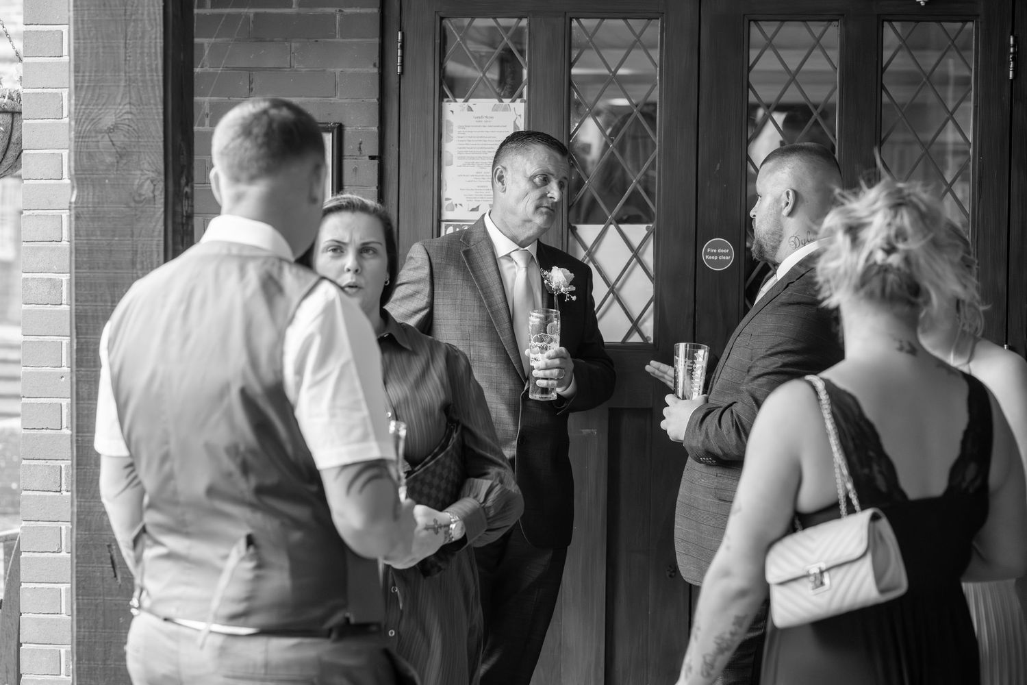 Guests gathered outside brick building during wedding celebration.