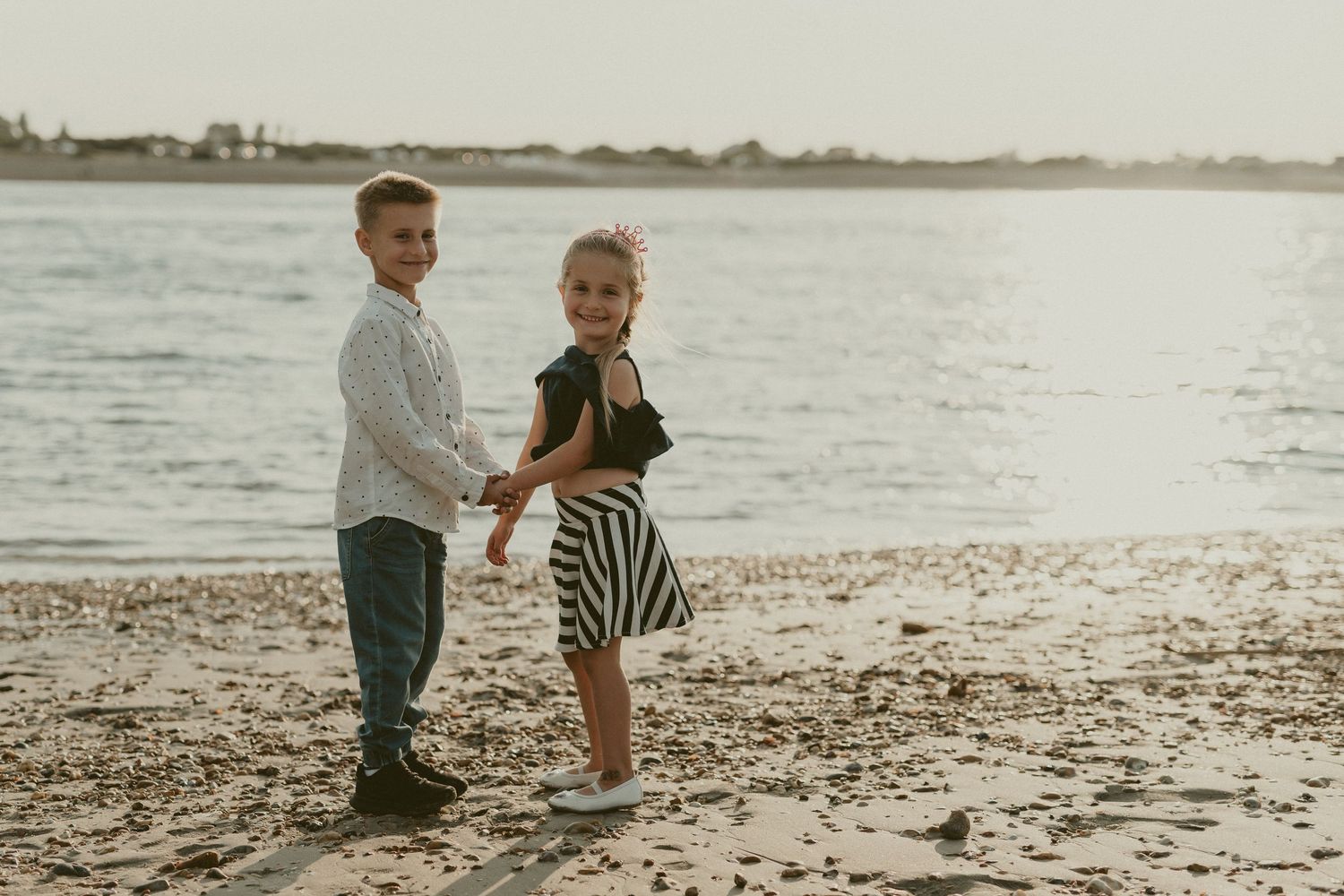 Family enjoying a playful moment together on the beach during golden hour.