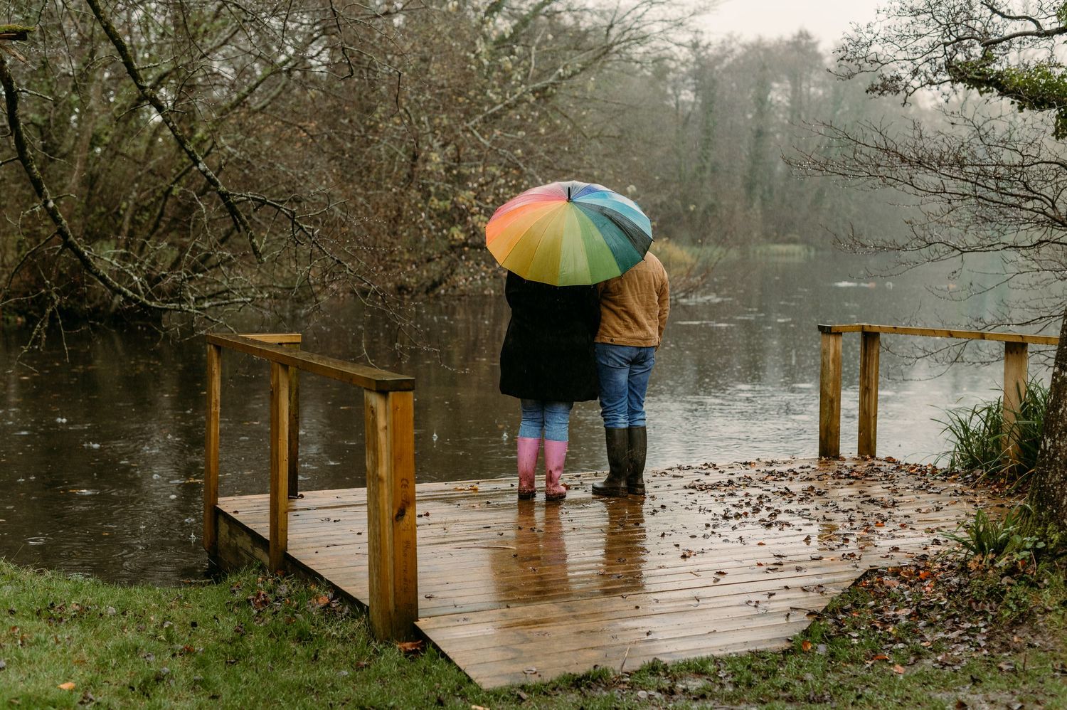 Wooden boardwalk over water on a misty autumn day with colorful trees.