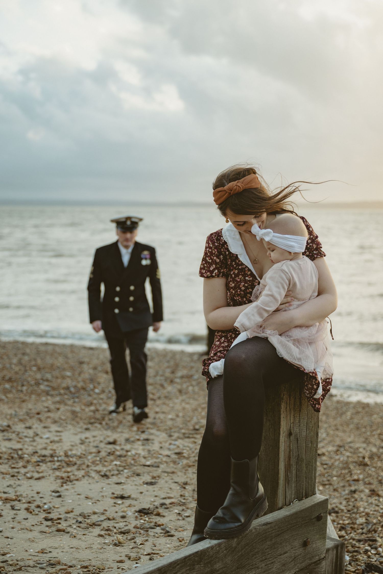 A scenic beach photoshoot with dramatic cloudy skies and waves in the background.