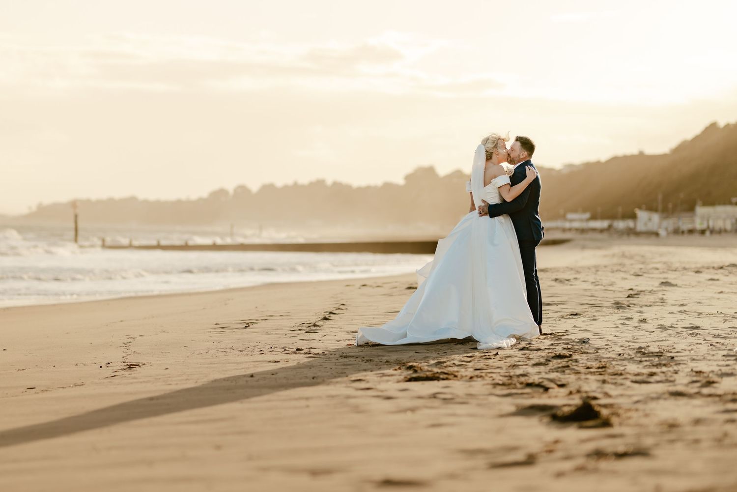 Romantic beach wedding photos at sunset with waves crashing in background.