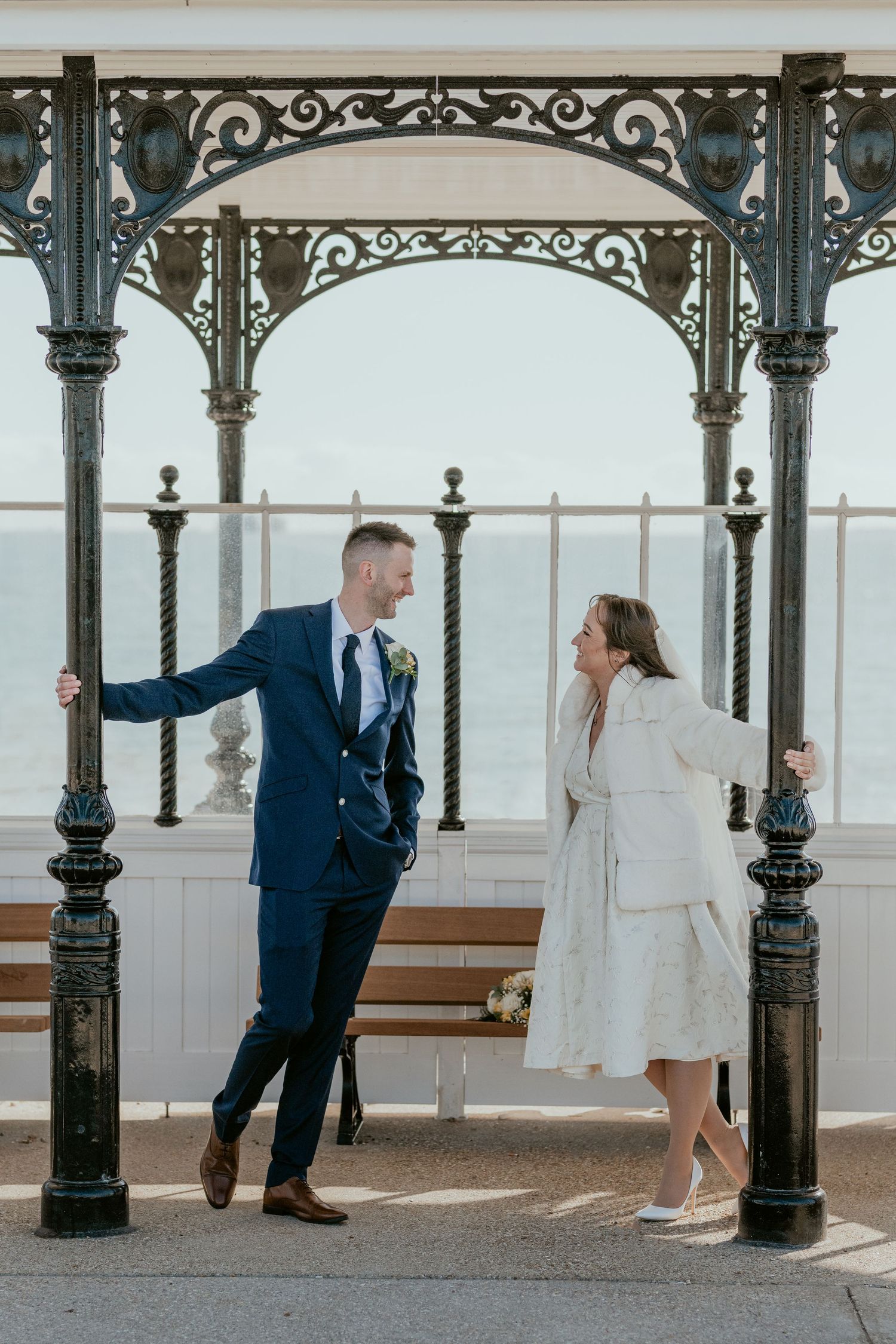 A seaside pavilion with ornate ironwork frames a romantic scene.