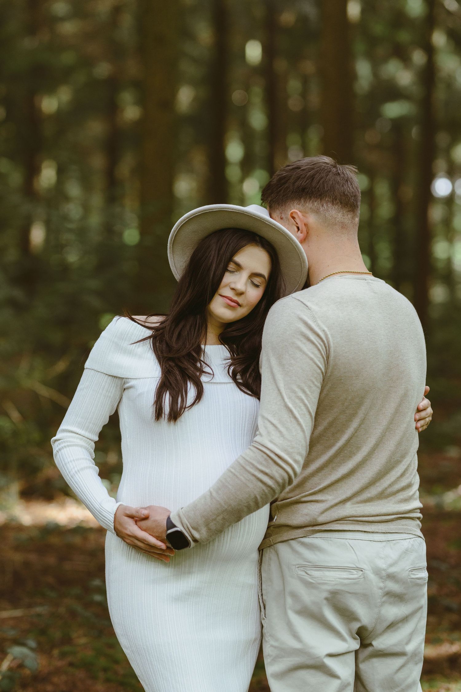 A series of romantic maternity photos captured in a peaceful forest setting.