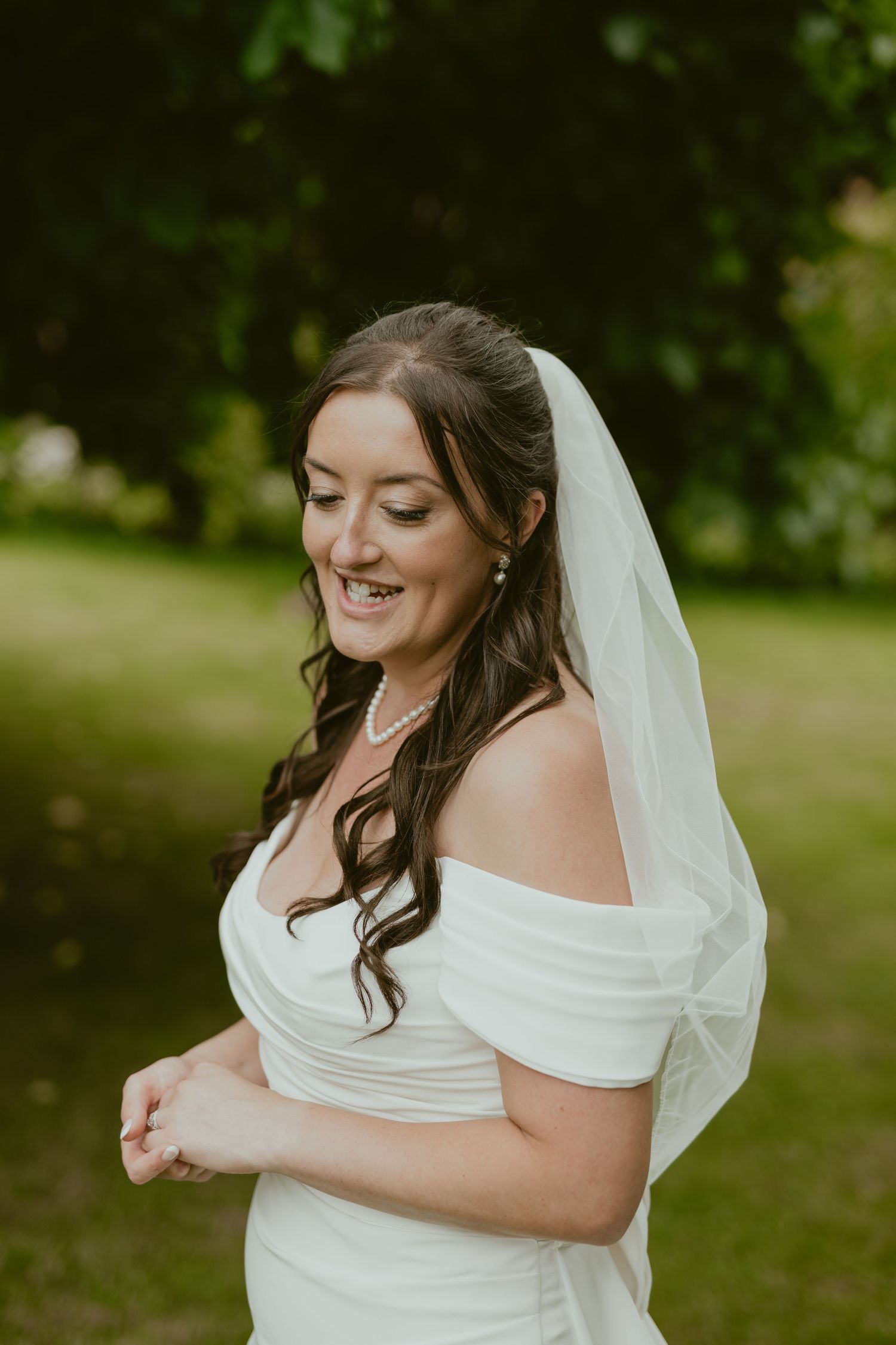 A bride in a white dress twirls joyfully in an outdoor garden setting.