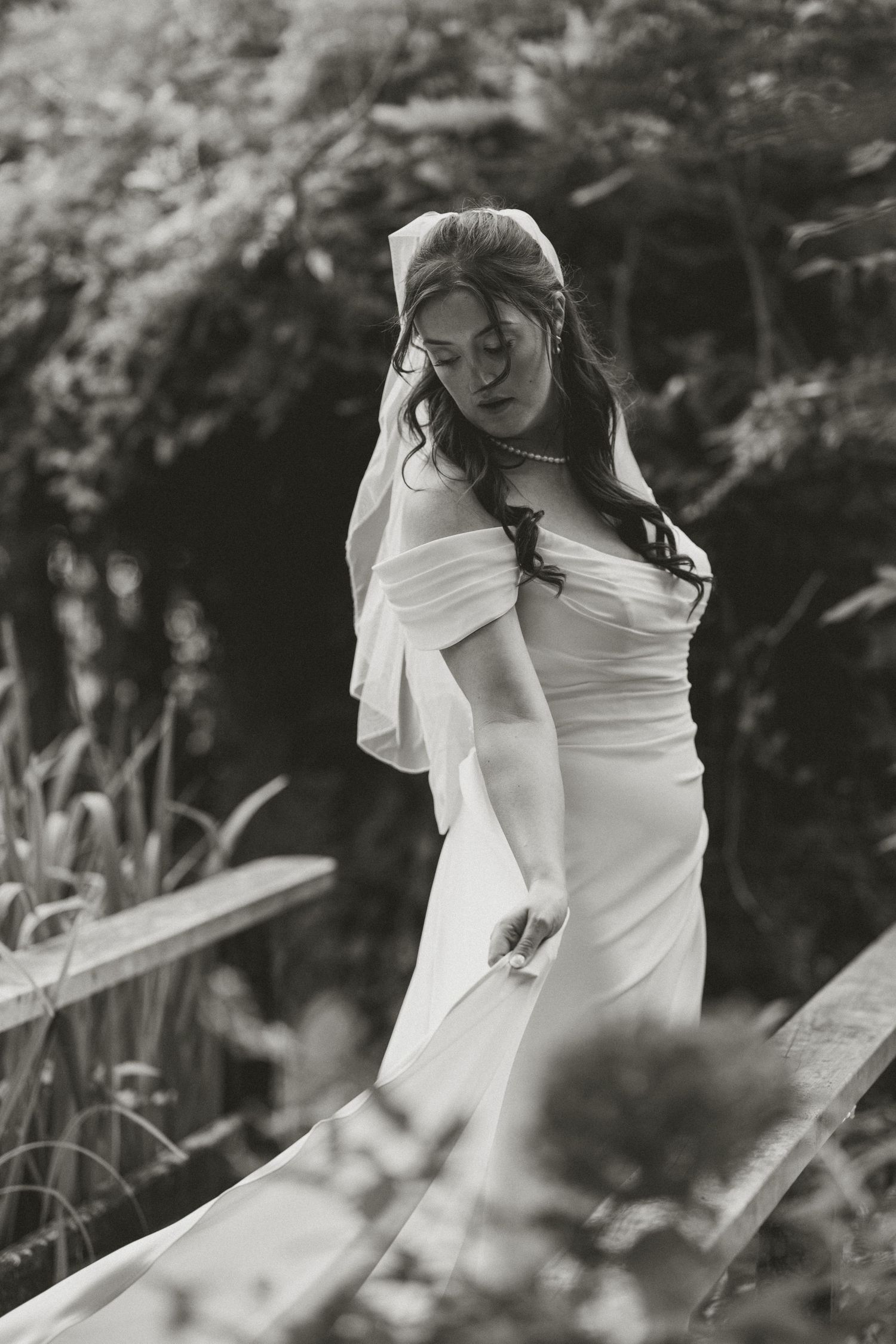 Artistic black and white bridal portrait on a rustic wooden bridge.