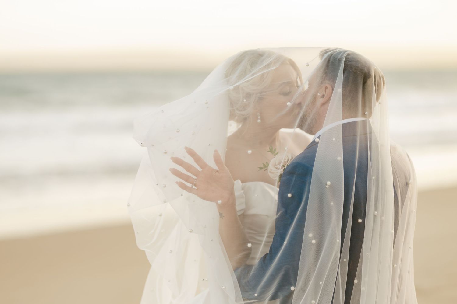 Intimate beach wedding portraits with flowing veil at golden hour.
