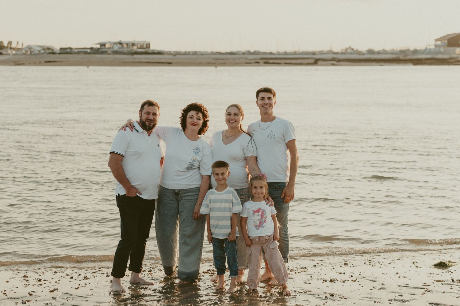 Family group photo on beach with ocean and sunset in background.