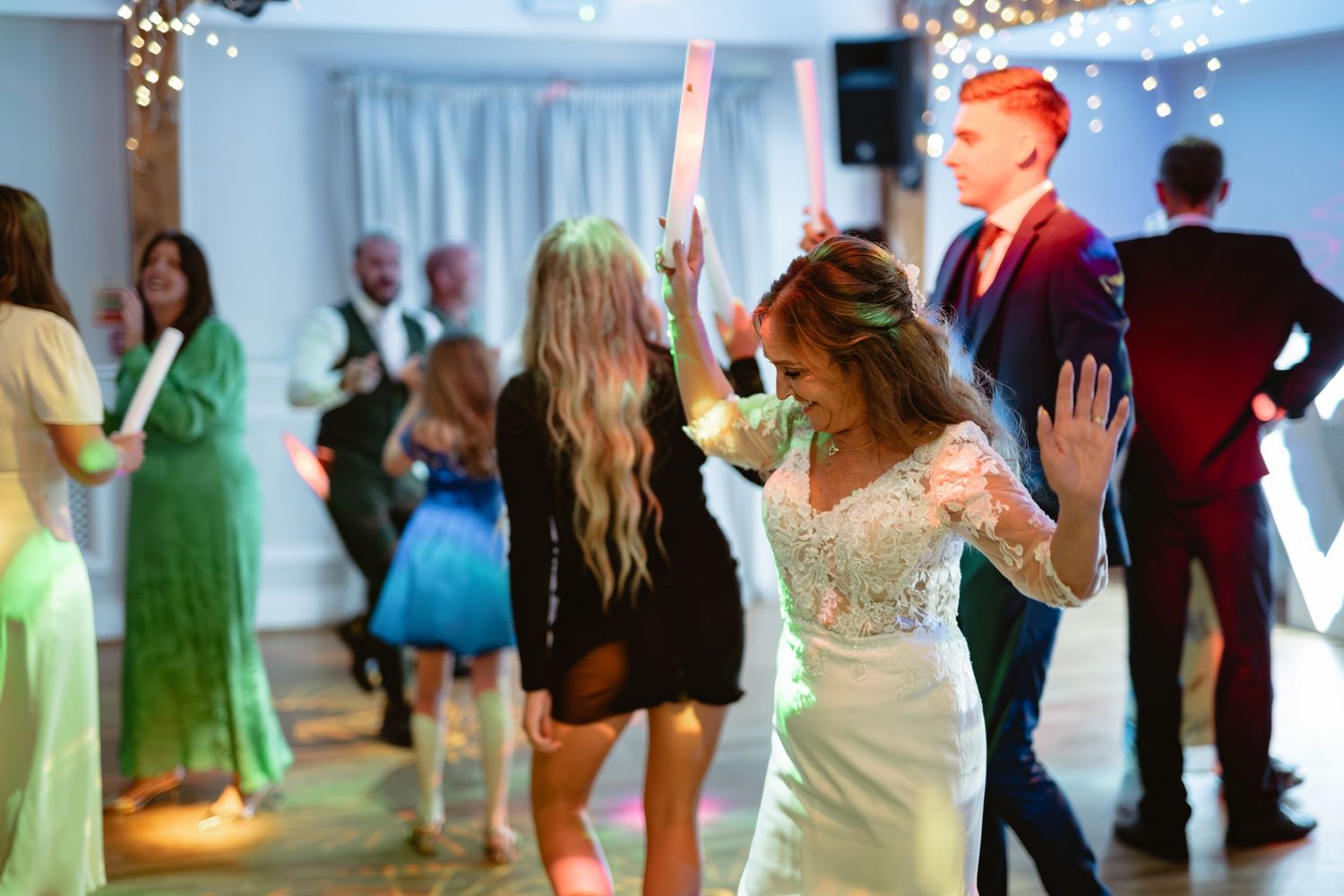 Wedding reception dance floor filled with guests celebrating under blue lighting and decorative elements.