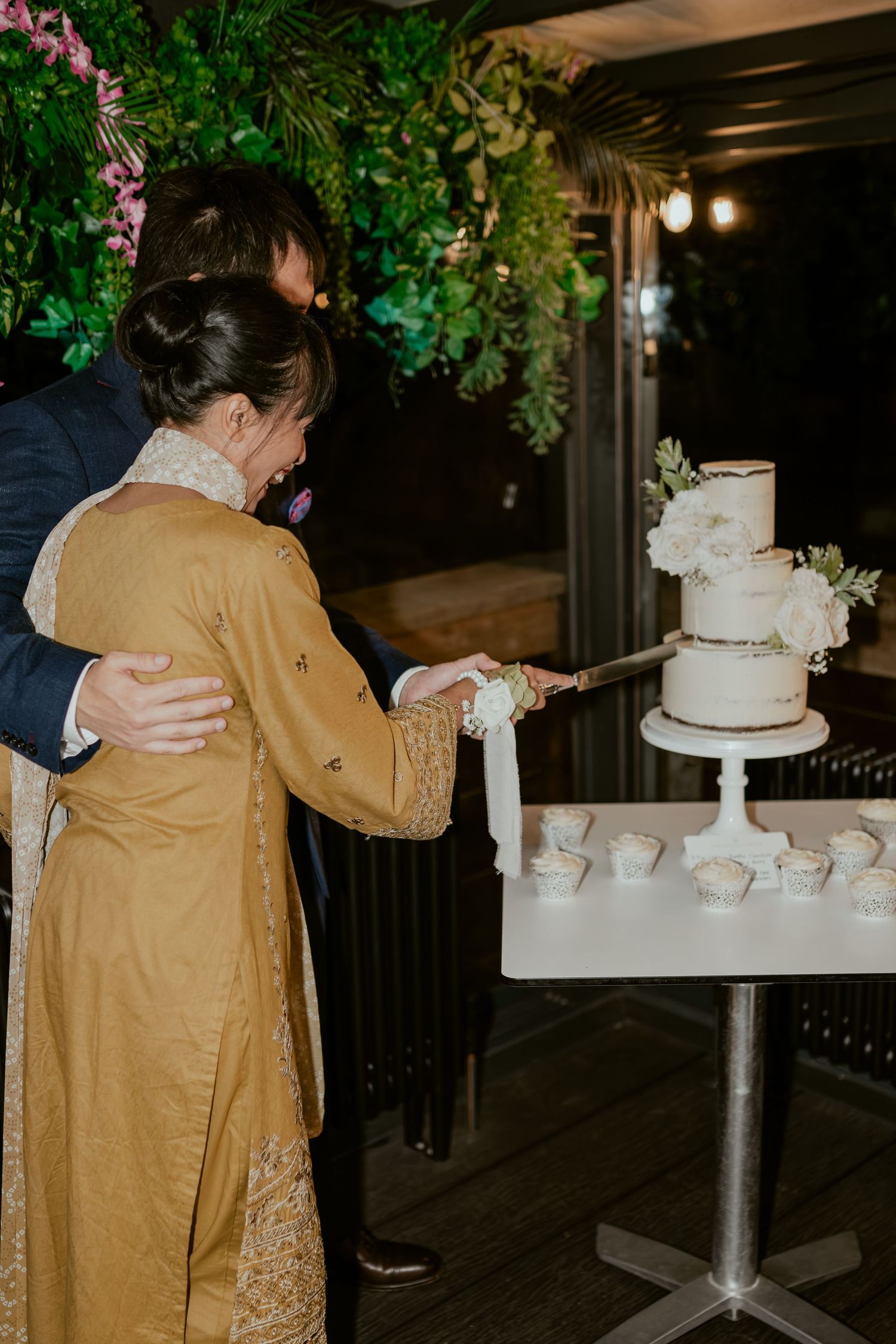 Wedding reception setup with white tiered cake and floral decorations.
