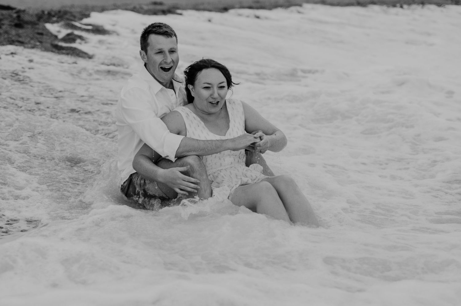 Black and white photo of a couple relaxing on a sandy beach.