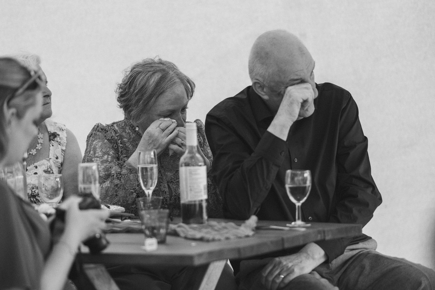 Candid black and white photo of wedding guests sharing an emotional moment at reception.
