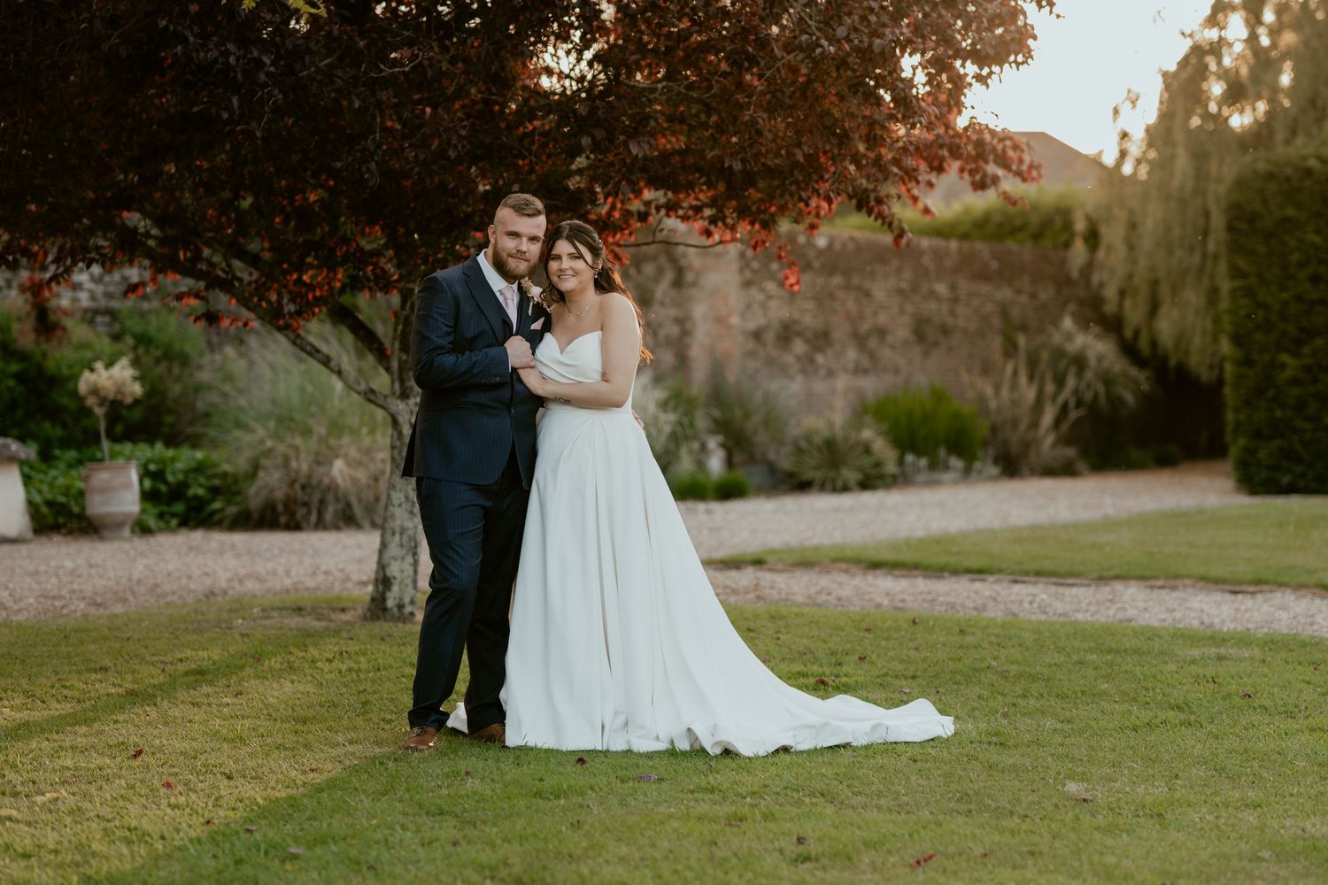 Wedding couple poses for romantic sunset photos on venue grounds.