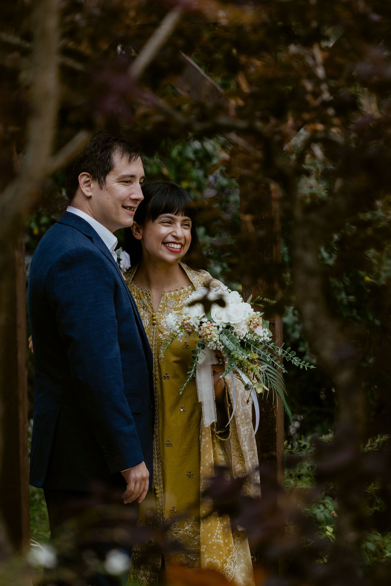 Couple sharing joyful moments in wooded outdoor setting with autumn foliage.