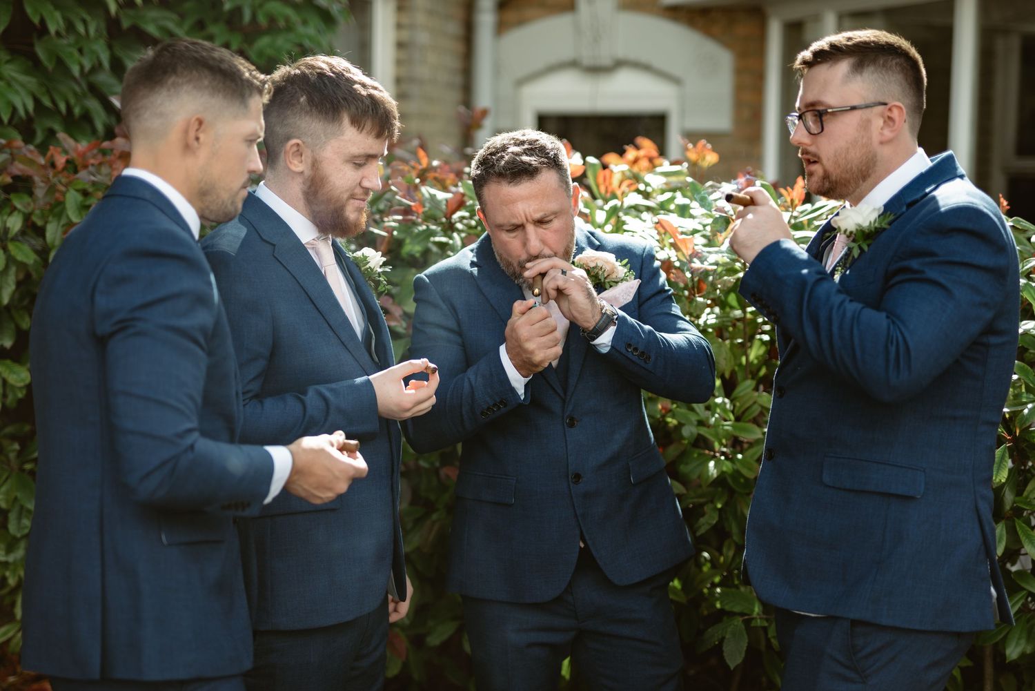 Groomsmen in navy suits sharing lighthearted moment outdoors.