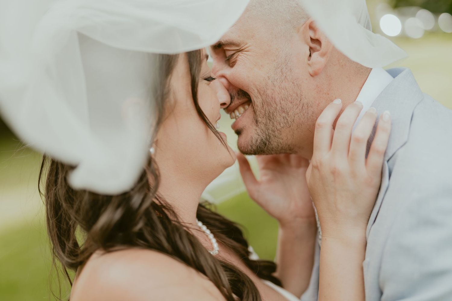 Intimate wedding moment captured through a delicate veil in natural lighting.