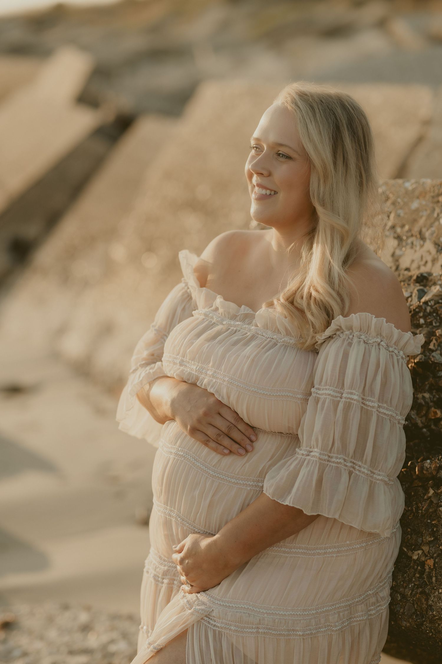 Intimate maternity portraits on a beach with soft golden light.