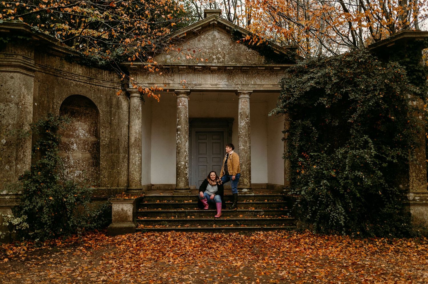 Historic stone building with arched windows surrounded by autumn foliage.
